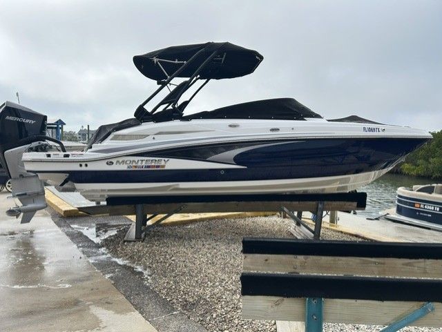 A Monterey M-45 boat on a dry dock, featuring a black canopy and blue-white paint.