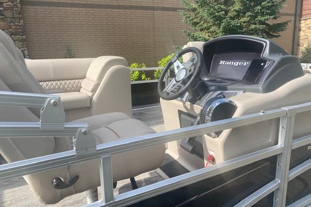 2025 Ranger Reata 223FC boat interior with beige seating and modern dashboard.