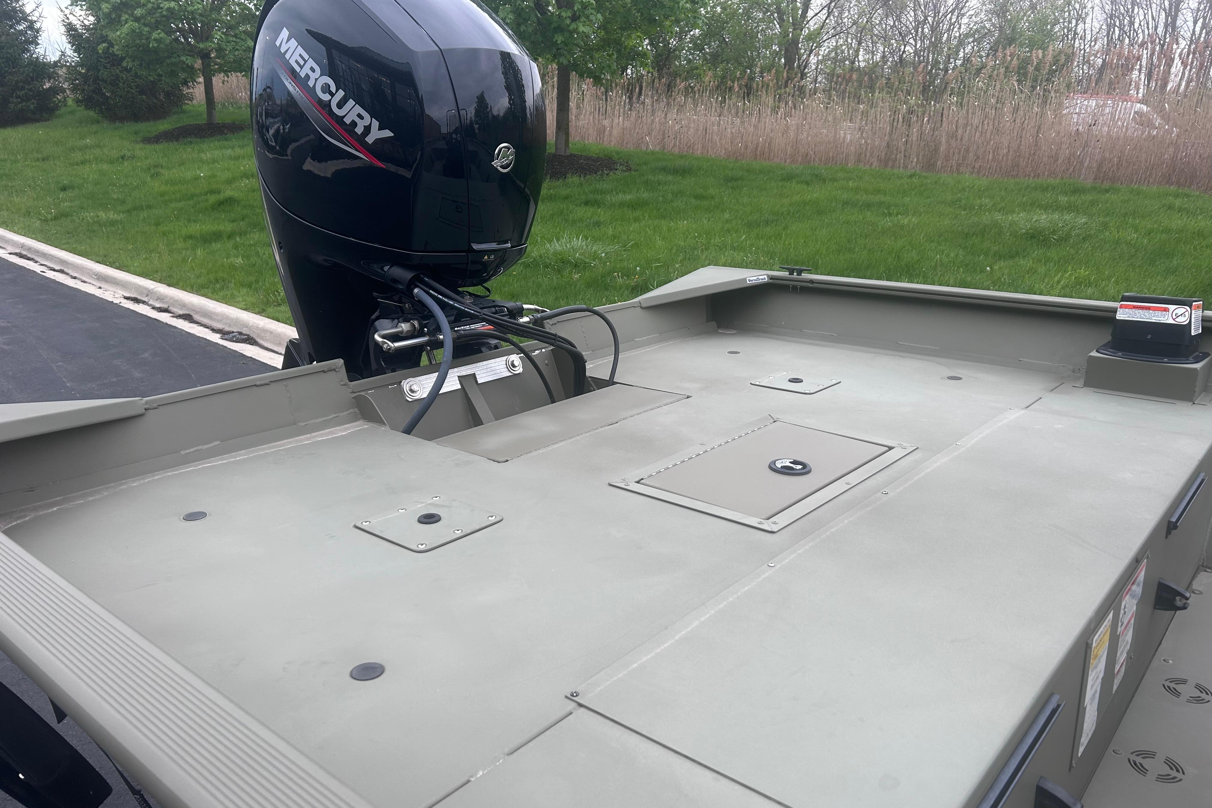 2024 Tracker Grizzly 2072 CC boat with Mercury outboard motor, parked on grass.