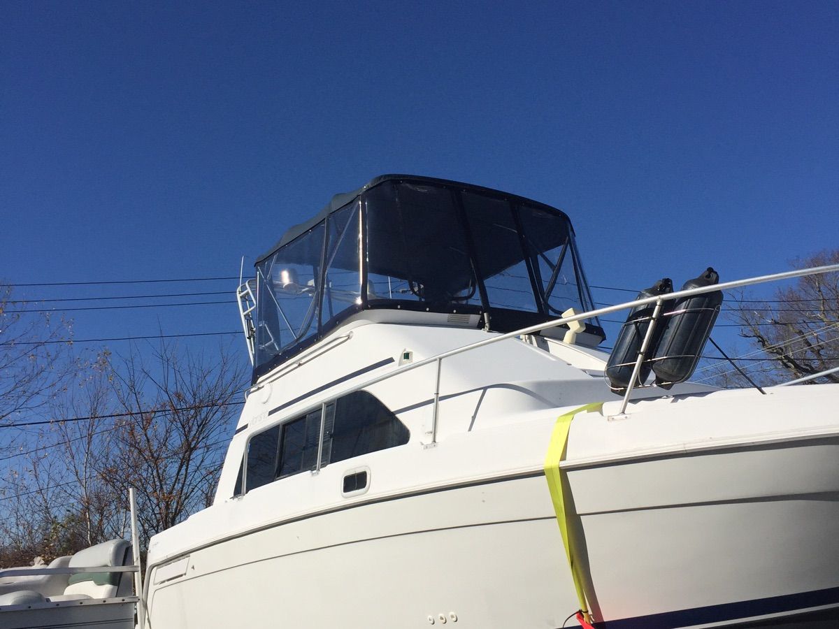 A 1998 Mainship 31 Sedan Bridge with an elevated helm and clear blue sky.