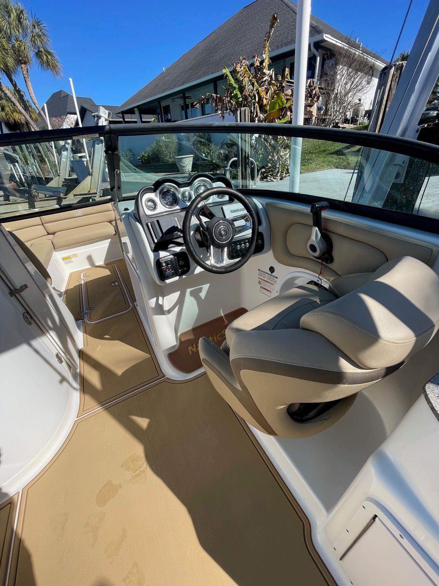 2019 NauticStar 243DC Sport Deck: Helm with steering wheel and gauges, beige seating.