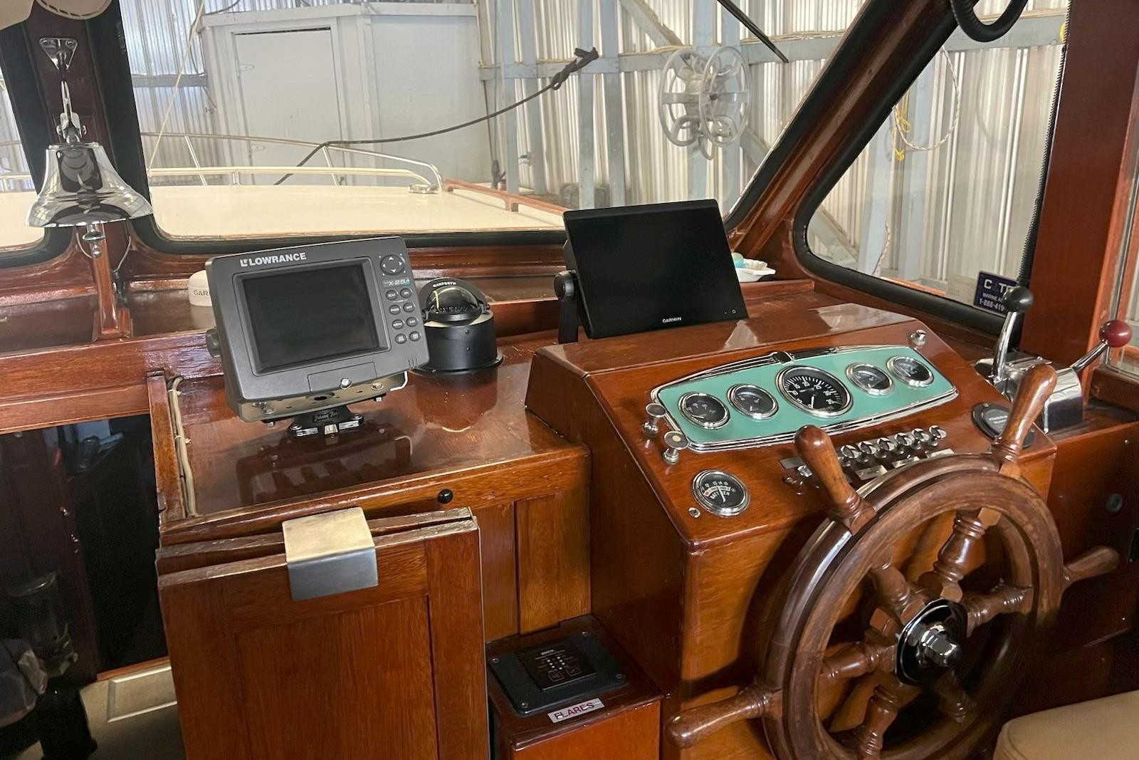 1963 Monk Custom Cruiser helm with wooden wheel, vintage gauges, and modern navigation equipment.