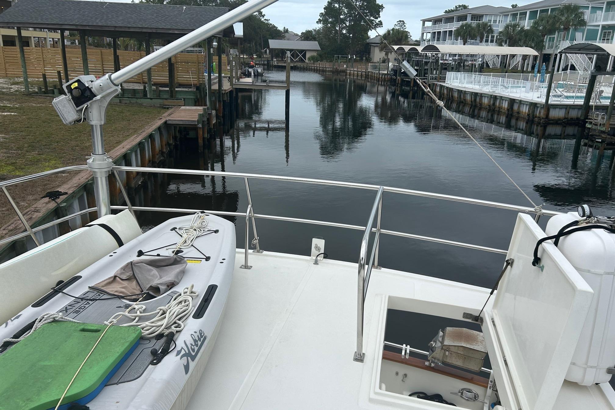 2006 Mariner Orient boat docked, featuring a paddleboard and calm waterfront view.