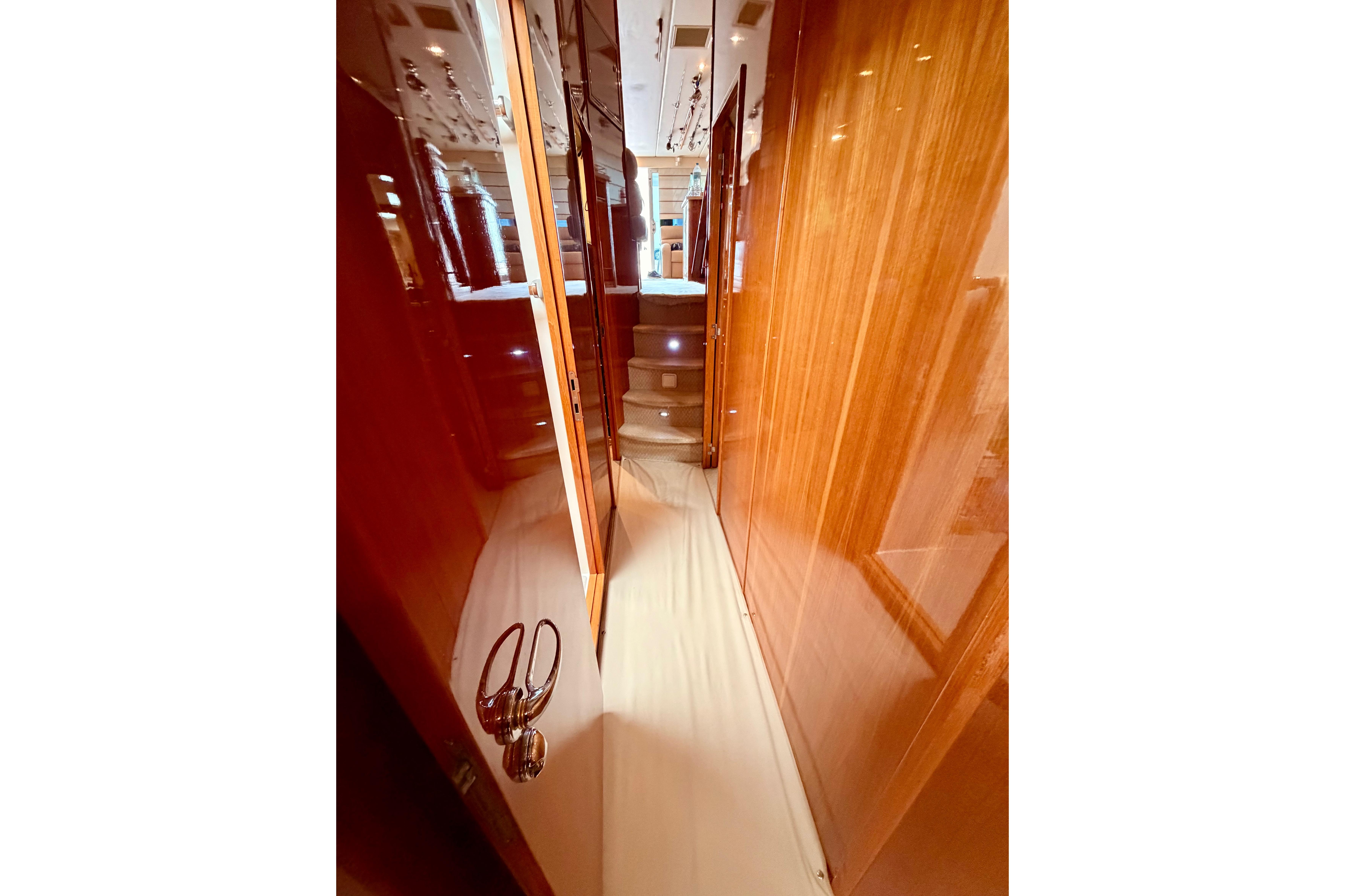 Narrow hallway with wooden paneling inside a 2004 Riviera 60 Flybridge yacht.