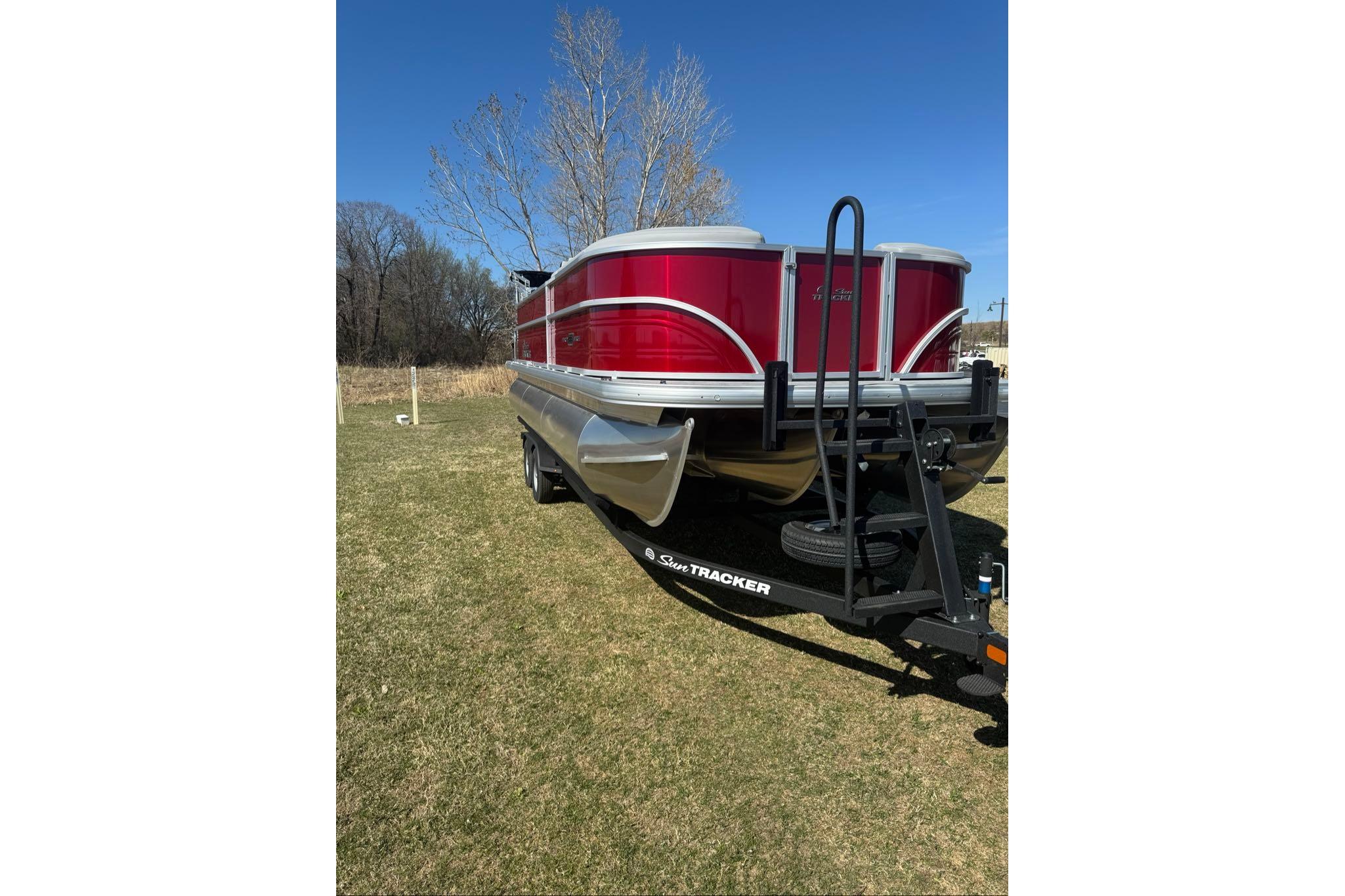 2026 Sun Tracker Party Barge 22 XP3 pontoon boat on trailer, parked on grass.