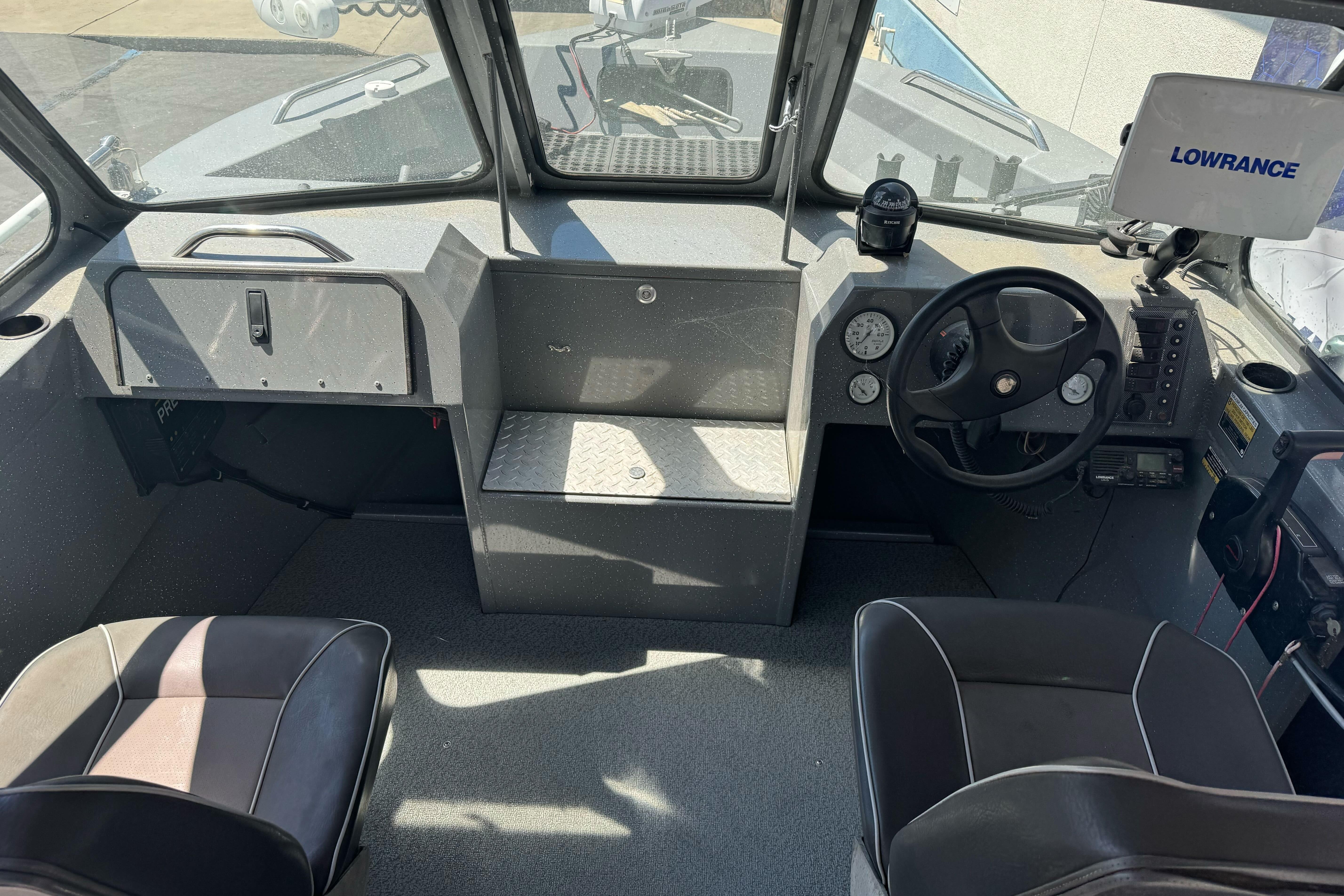 Interior of a 2014 River Hawk 19 GB boat with steering wheel and navigation equipment.
