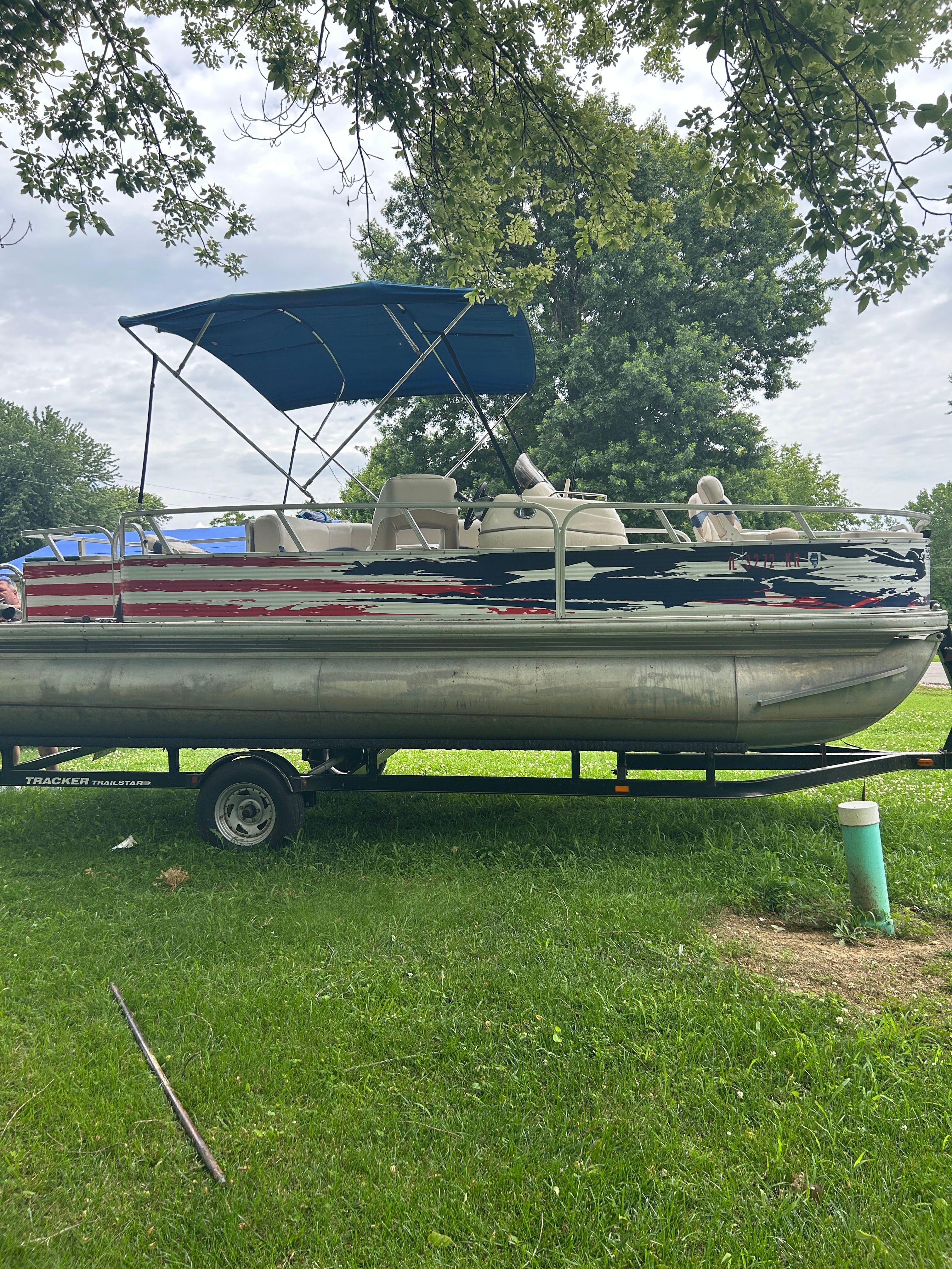 A 2008 Sun Tracker Fishin' Barge 21' on a trailer in a grassy area.