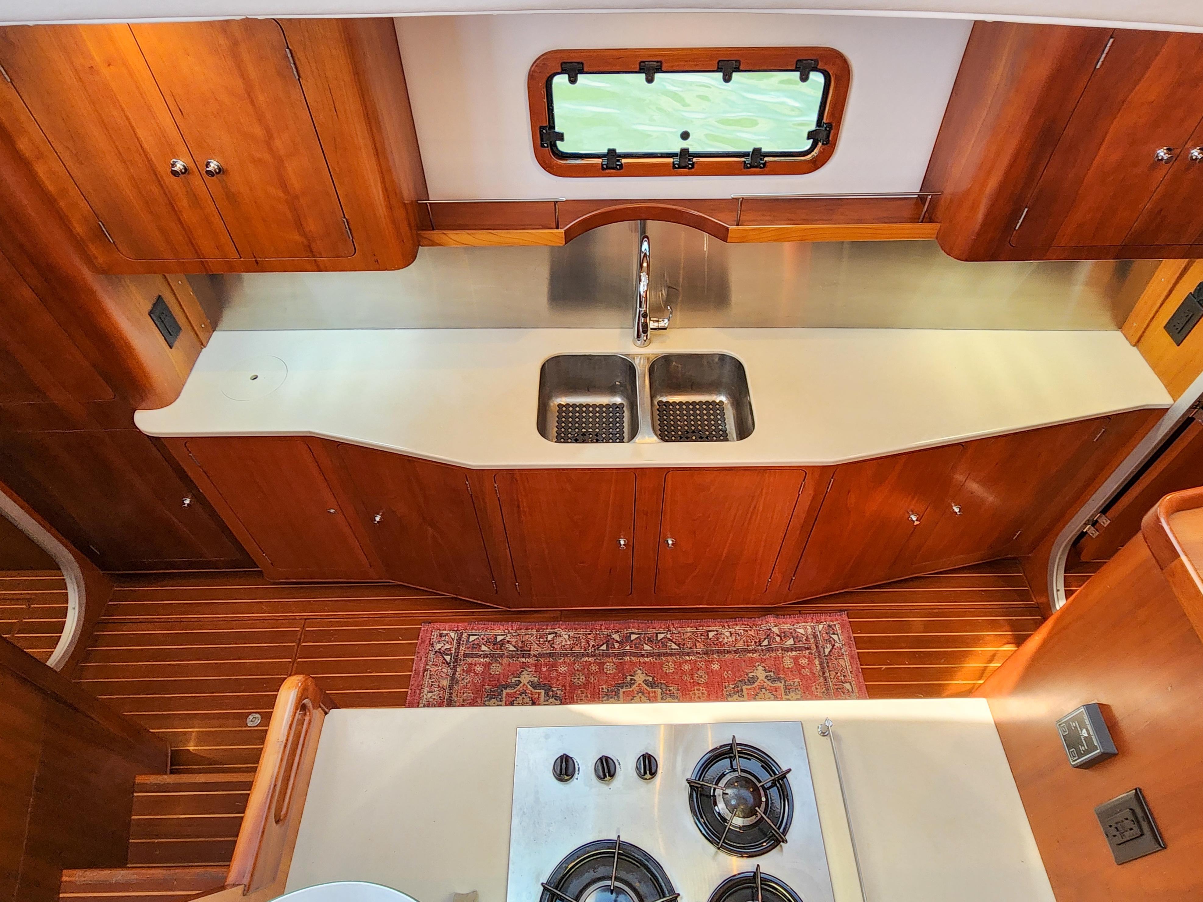 Luxurious Antares 44i 2014 yacht kitchen with wooden cabinetry, dual sink, and stove.