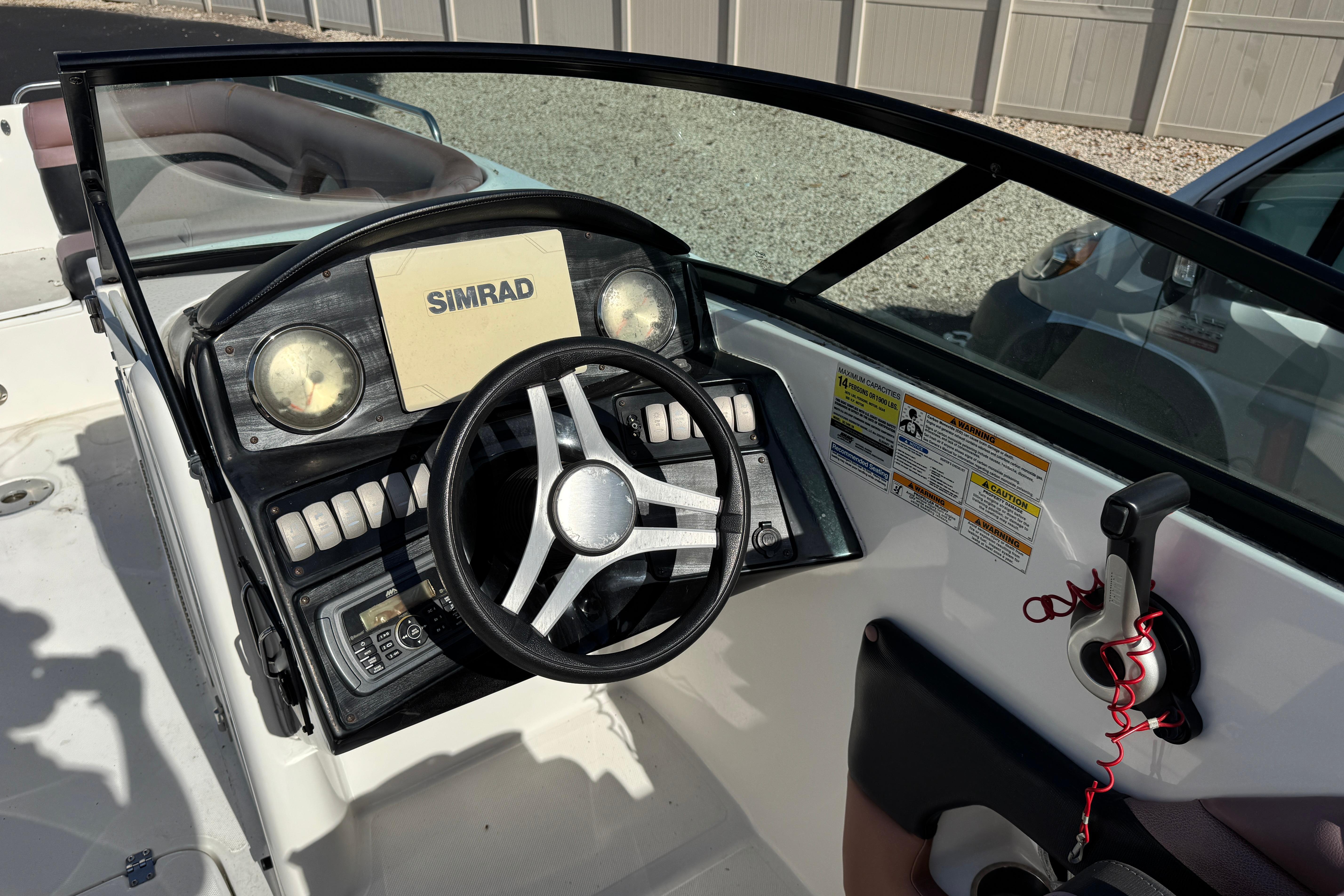 2018 Hurricane SunDeck 2400 OB boat dashboard with steering wheel and Simrad display.