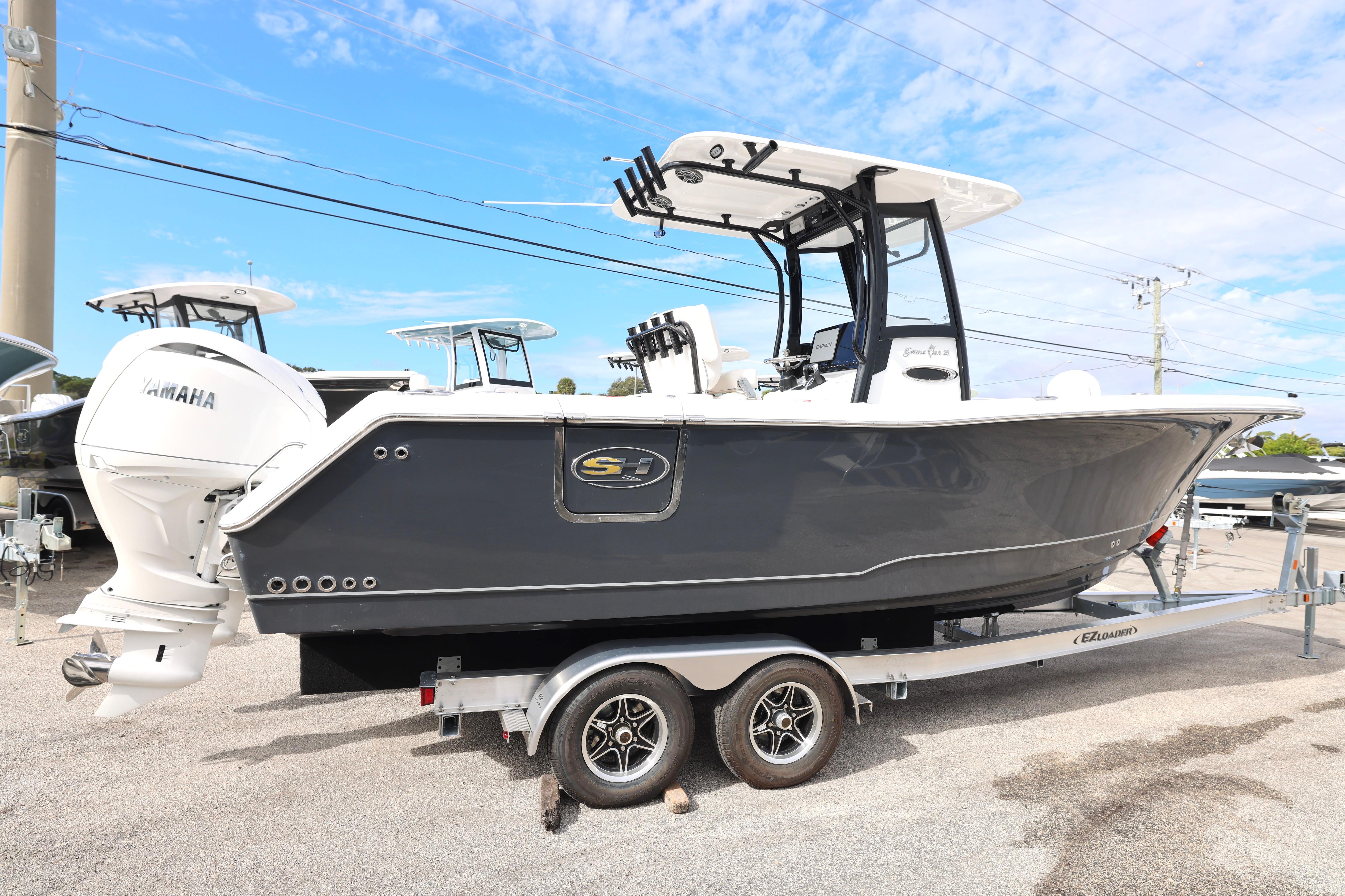 2026 Sea Hunt Gamefish 25 boat on trailer, featuring Yamaha engine, under clear blue sky.