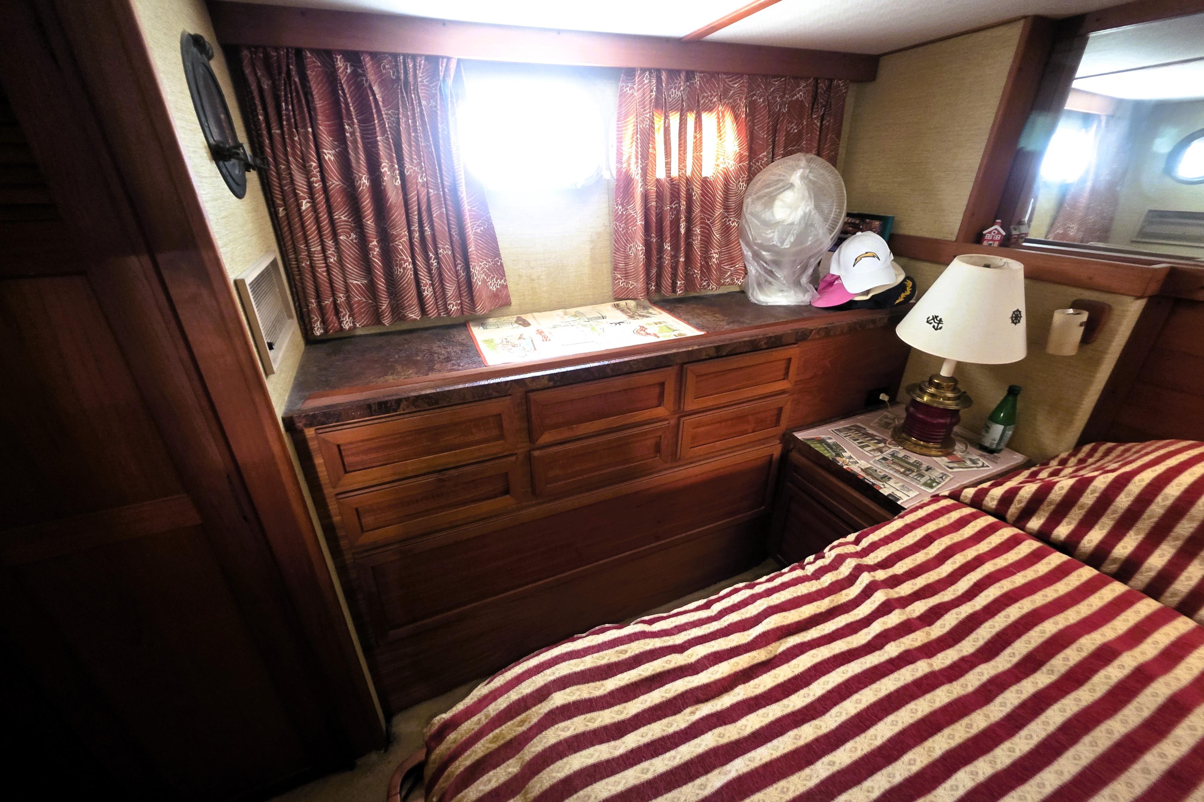 1979 Trojan 44 Motor Yacht interior with striped bedding, wooden cabinetry, and decorative lamp.