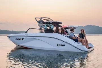 2026 Yamaha Boats 222XE on serene water at sunset with passengers enjoying the ride.