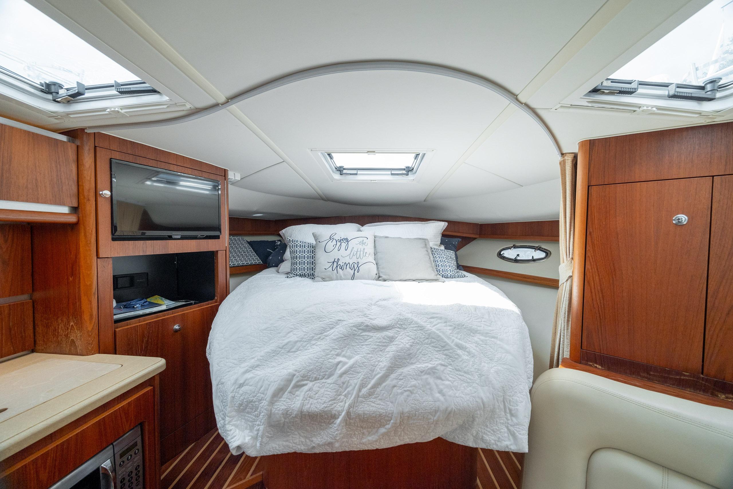 Luxurious cabin interior of 2004 Tiara Yachts 3200 Open with cozy bed and wooden finishes.