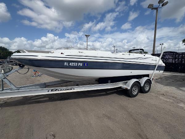 2014 Hurricane SunDeck Sport 232 OB boat on trailer under cloudy sky.