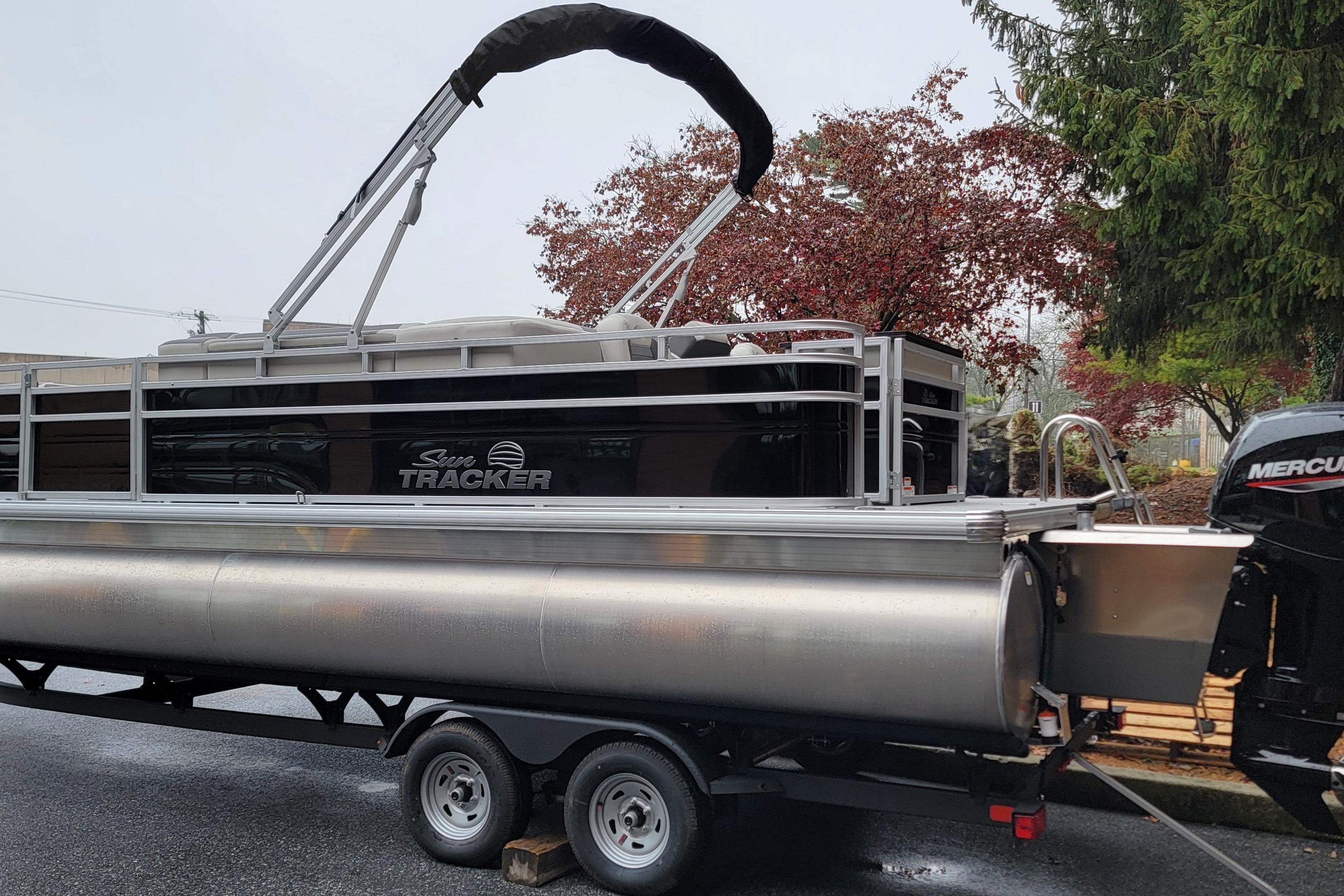 2026 Sun Tracker Fishin' Barge 22 XP3 pontoon boat on trailer, parked outdoors.