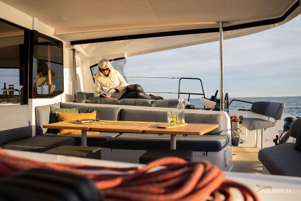 2025 Nautitech 48 Open yacht interior with person relaxing, reading on deck.