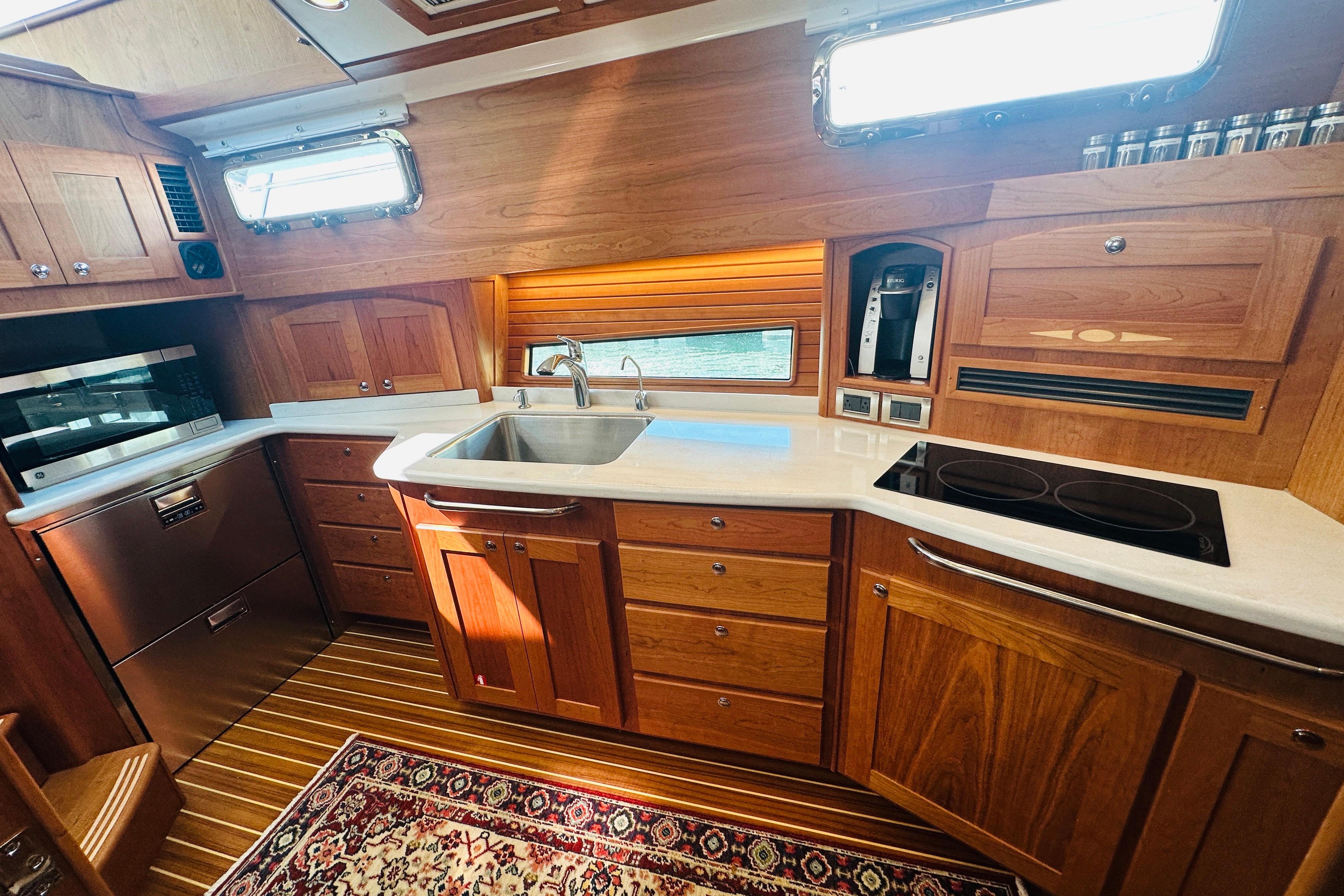 Luxurious 2025 Sabre 48 Salon Express yacht kitchen with wood cabinetry and modern appliances.