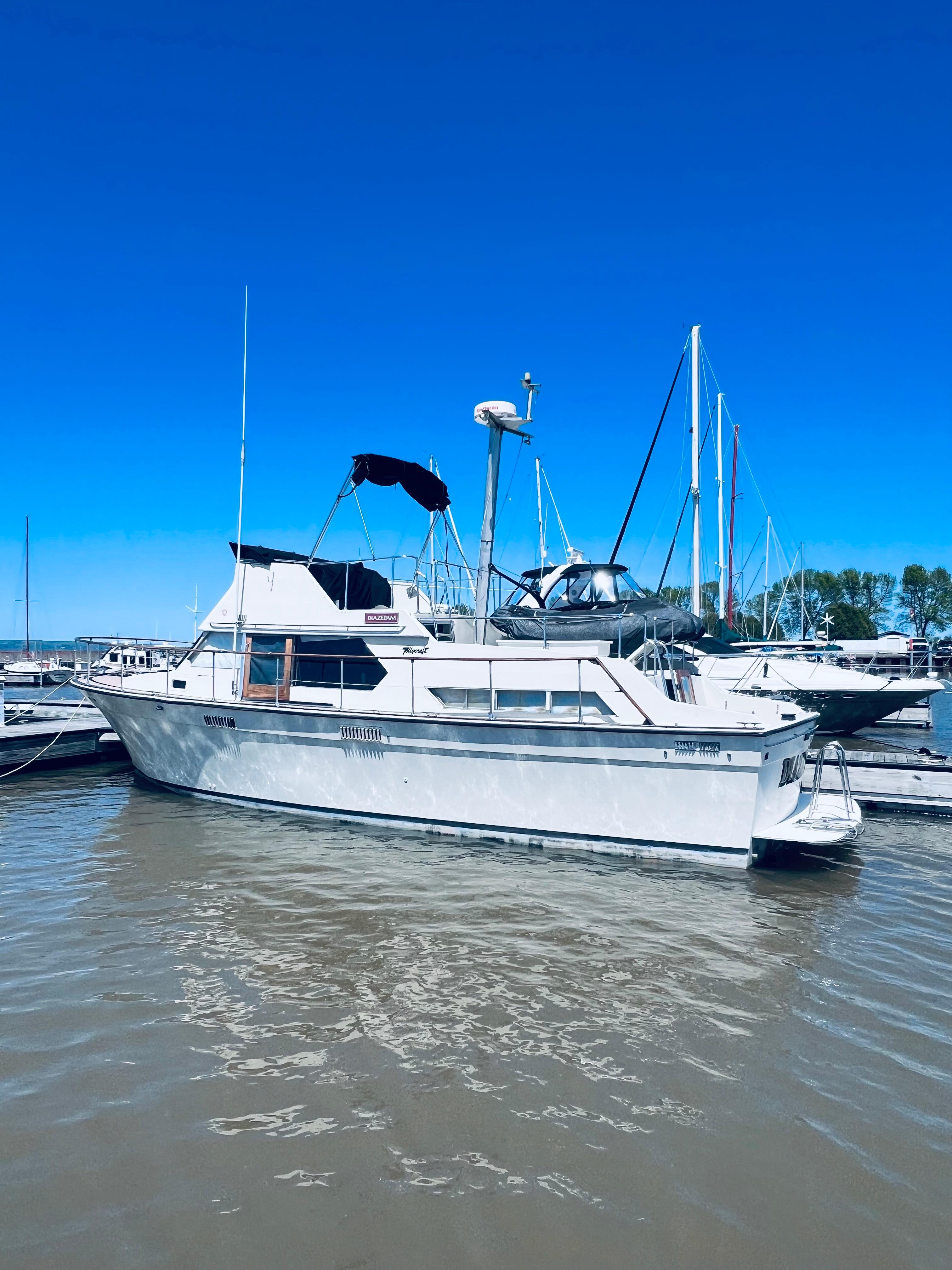 1974 Tollycraft 40 Tri-Cabin Motoryacht docked in a marina under clear blue skies.