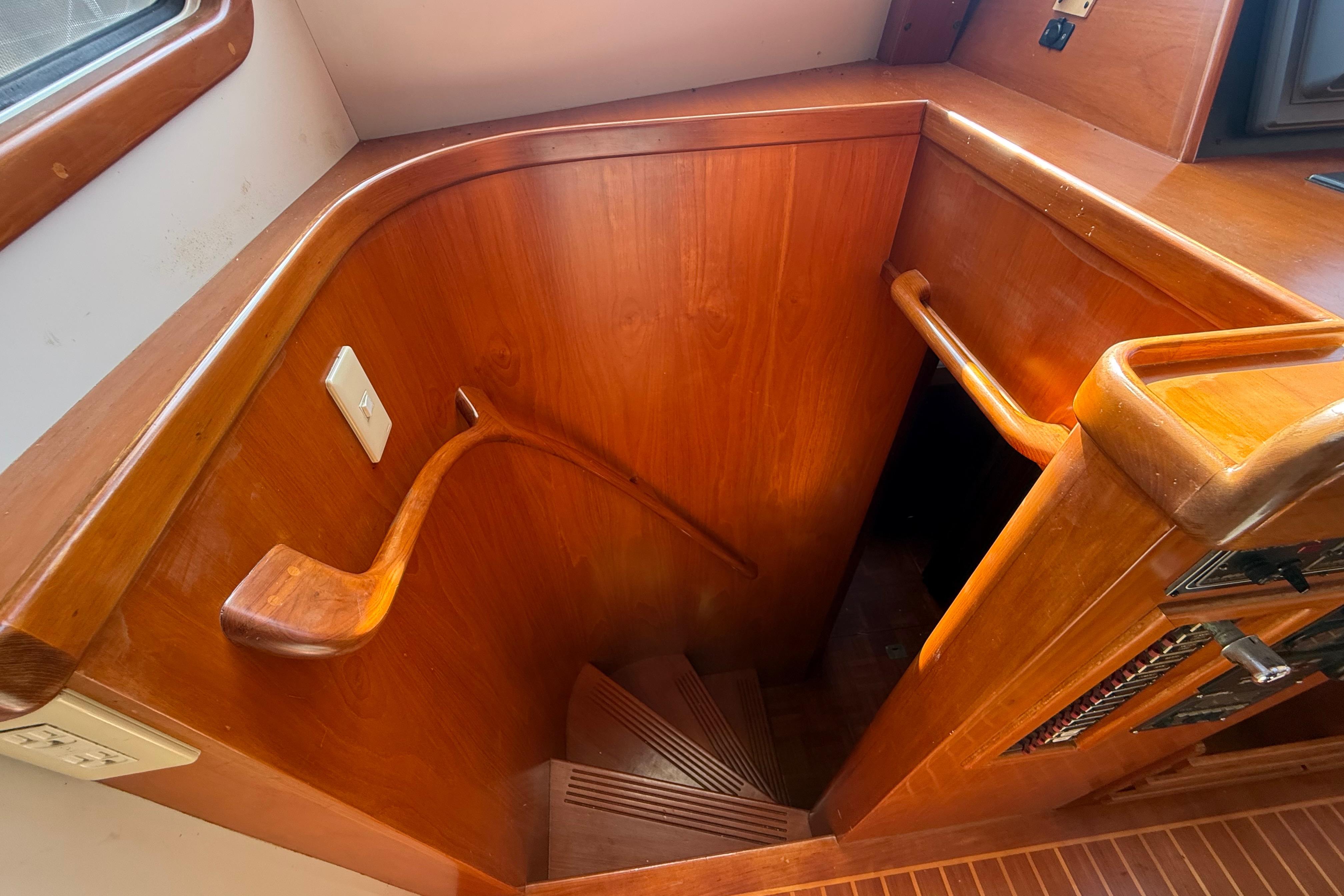 Wooden staircase inside a 2001 Kadey-Krogen 39 yacht, featuring elegant handrails and paneling.
