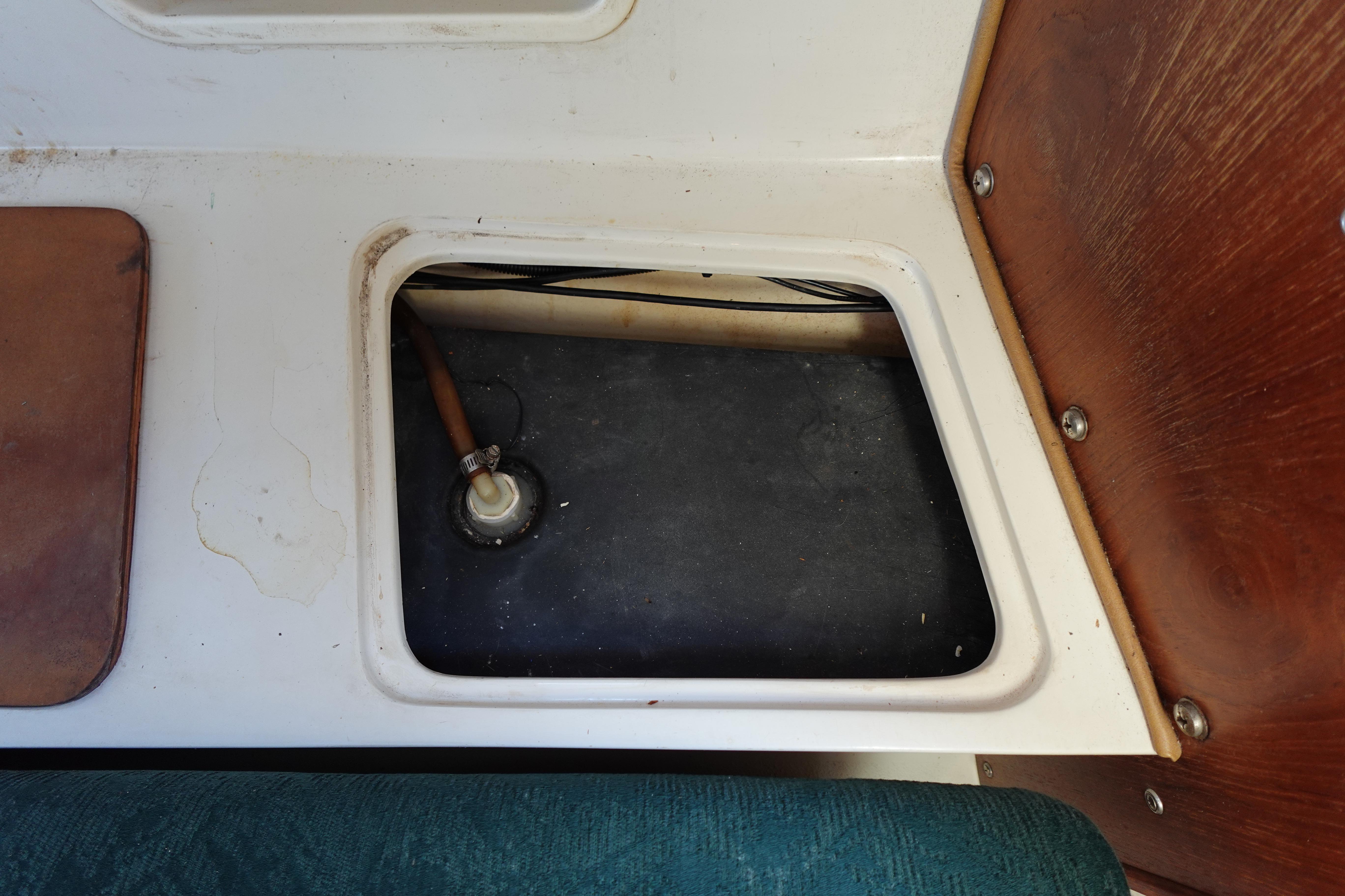 Open compartment in 1997 Catalina 28 sailboat interior, showing plumbing and storage area.