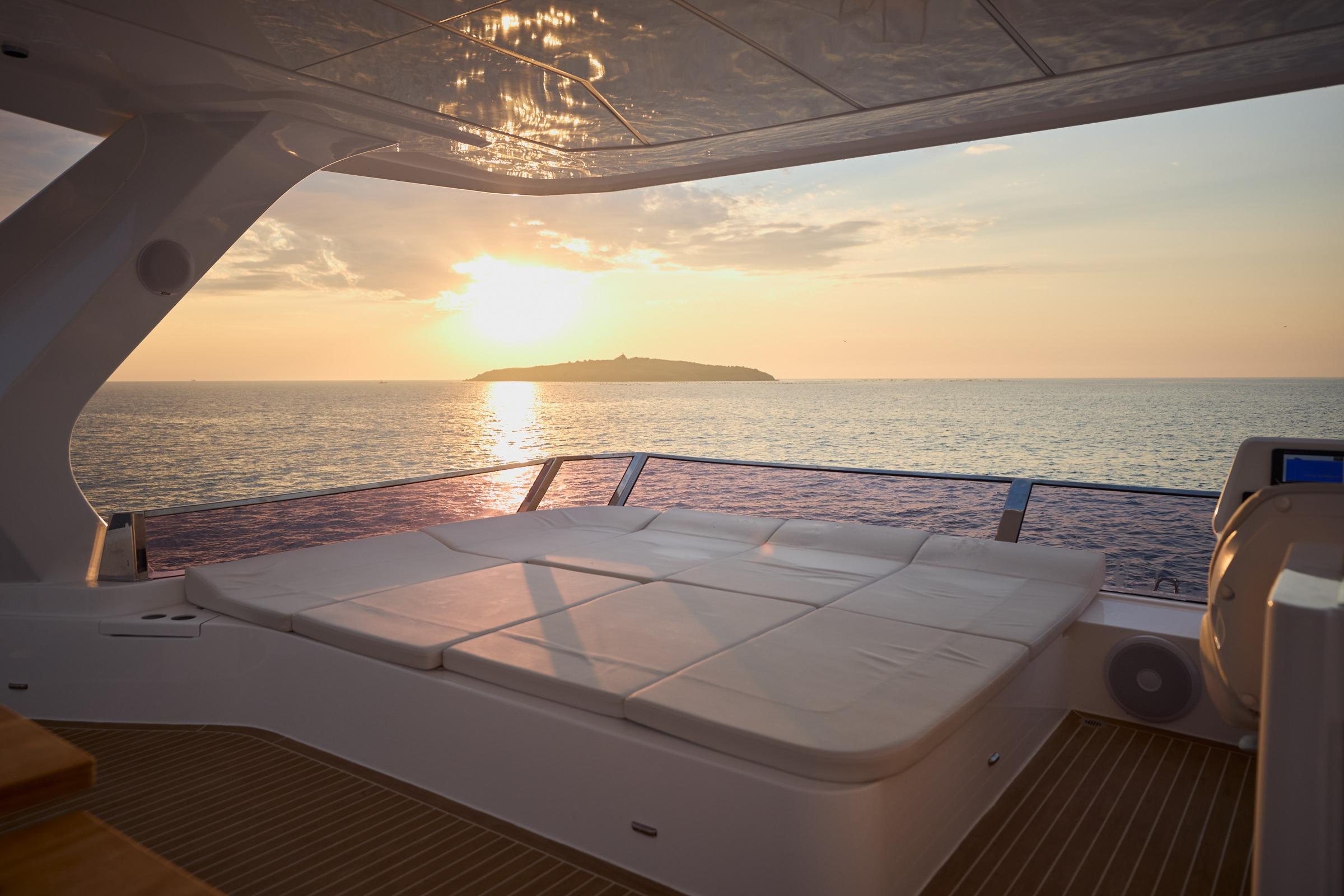 Luxurious Omaya 50 Power Catamaran at sunset, featuring spacious deck and serene ocean view.