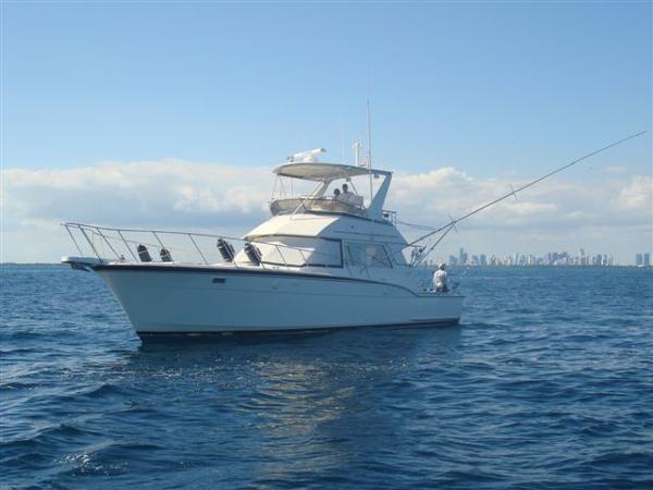 1985 Hatteras 45 Convertible yacht on open sea with city skyline.