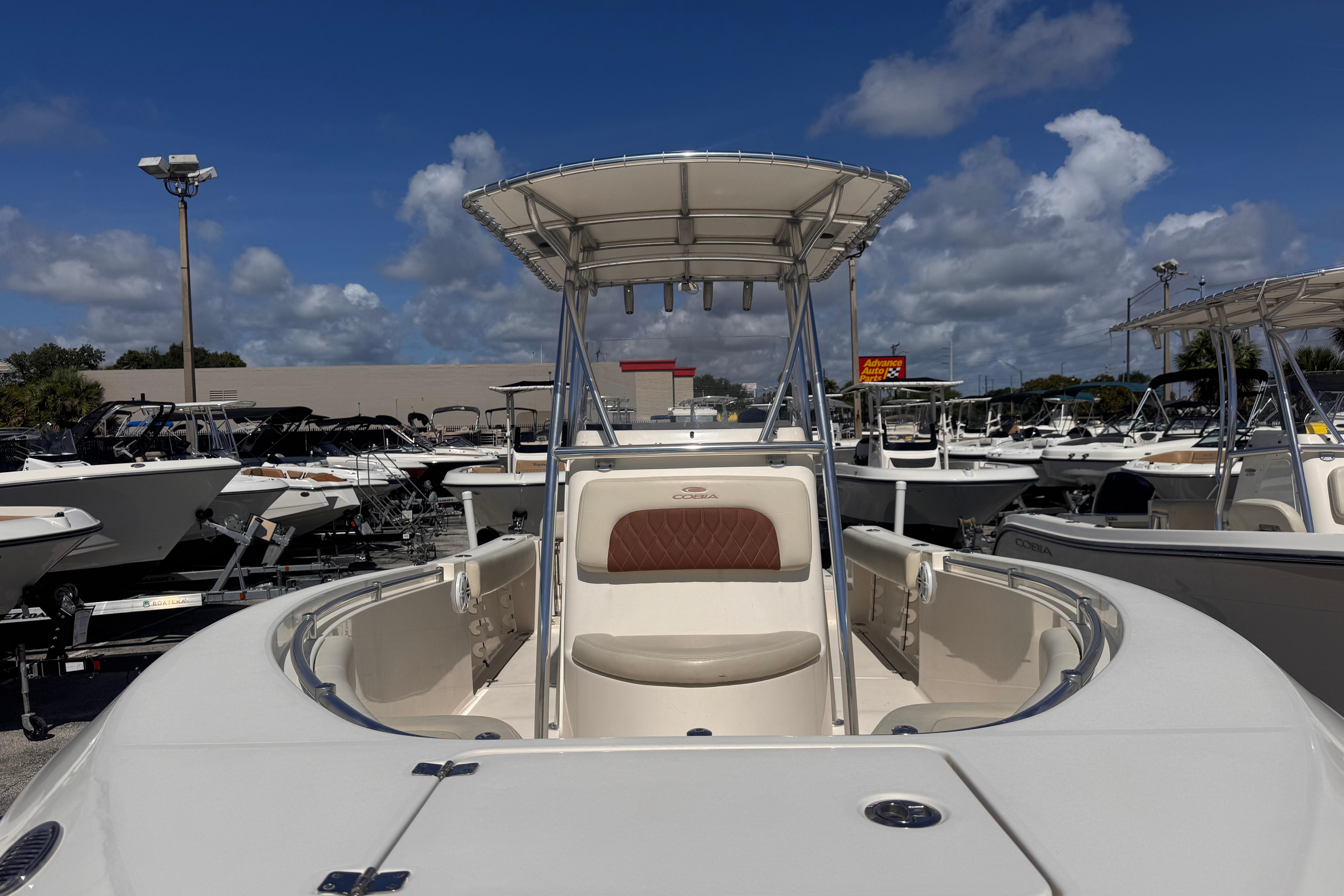 2023 Cobia 237 Center Console boat displayed at a dealership under a clear blue sky.