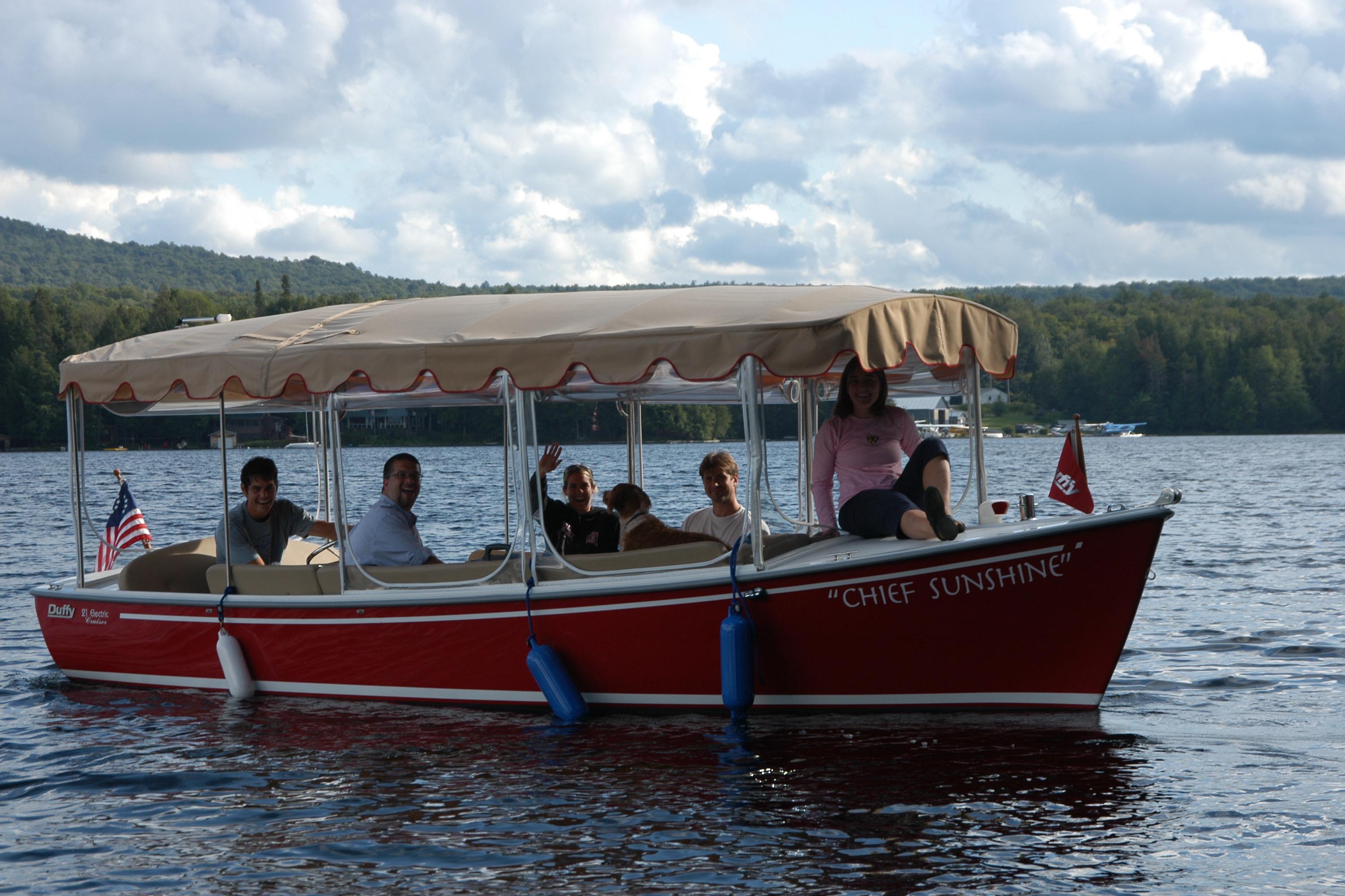 Red 2004 Duffy 21 Classic boat named "Chief Sunshine" on a lake with passengers.