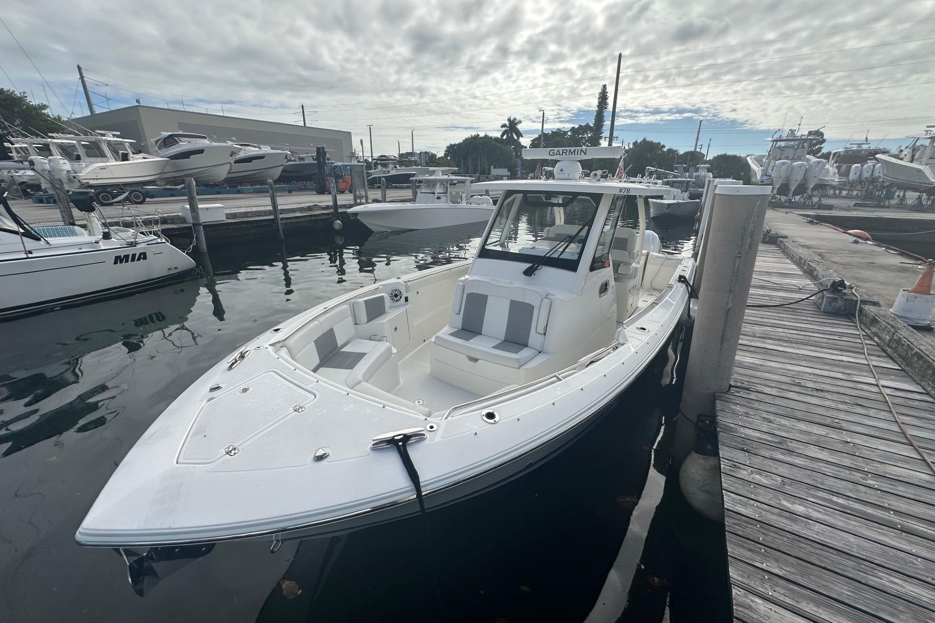 2023 Pursuit S 328 Sport boat docked at marina under cloudy sky.