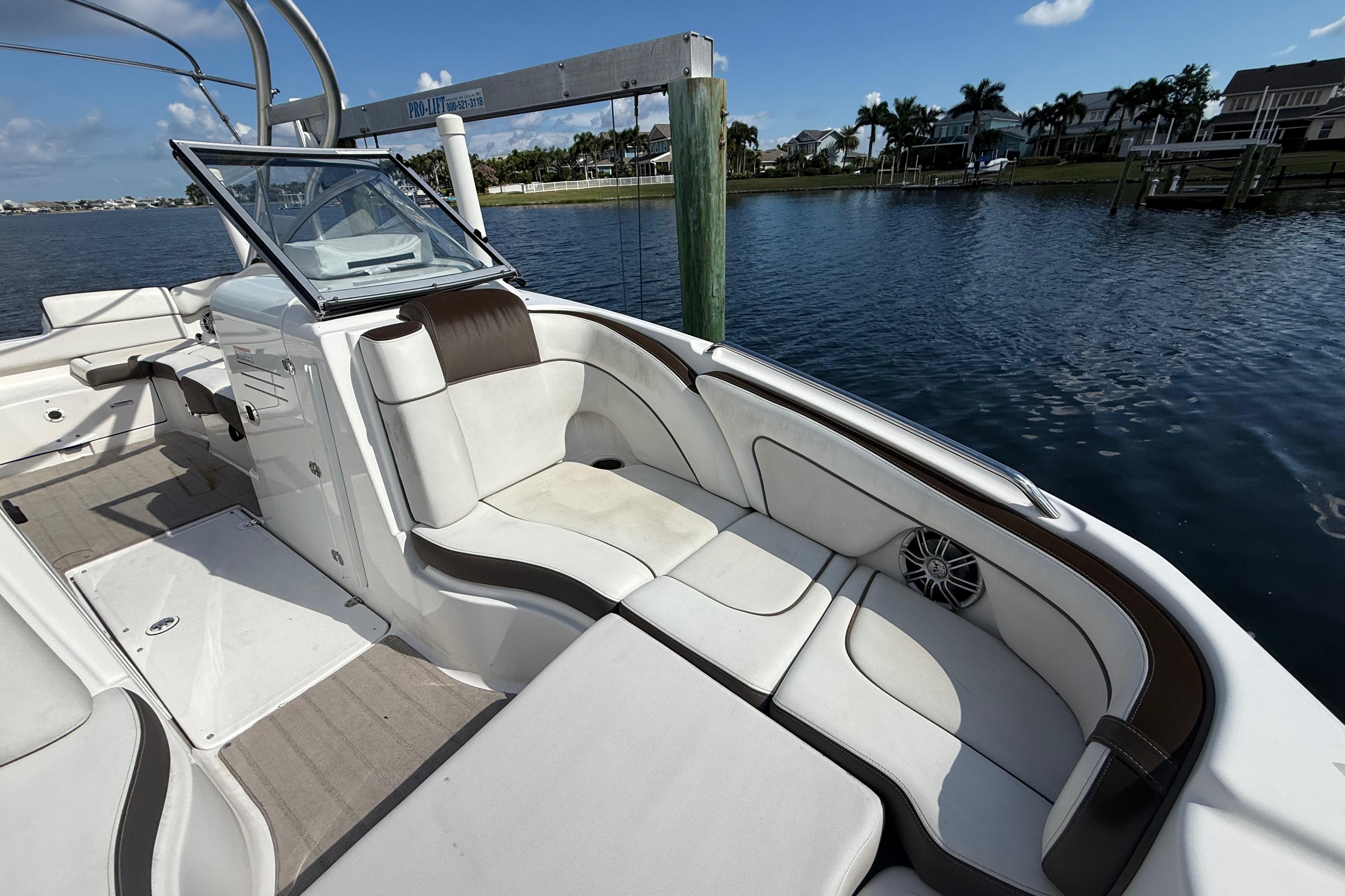 2014 Yamaha Boats 242 Limited S interior with white seating, docked by calm waters.
