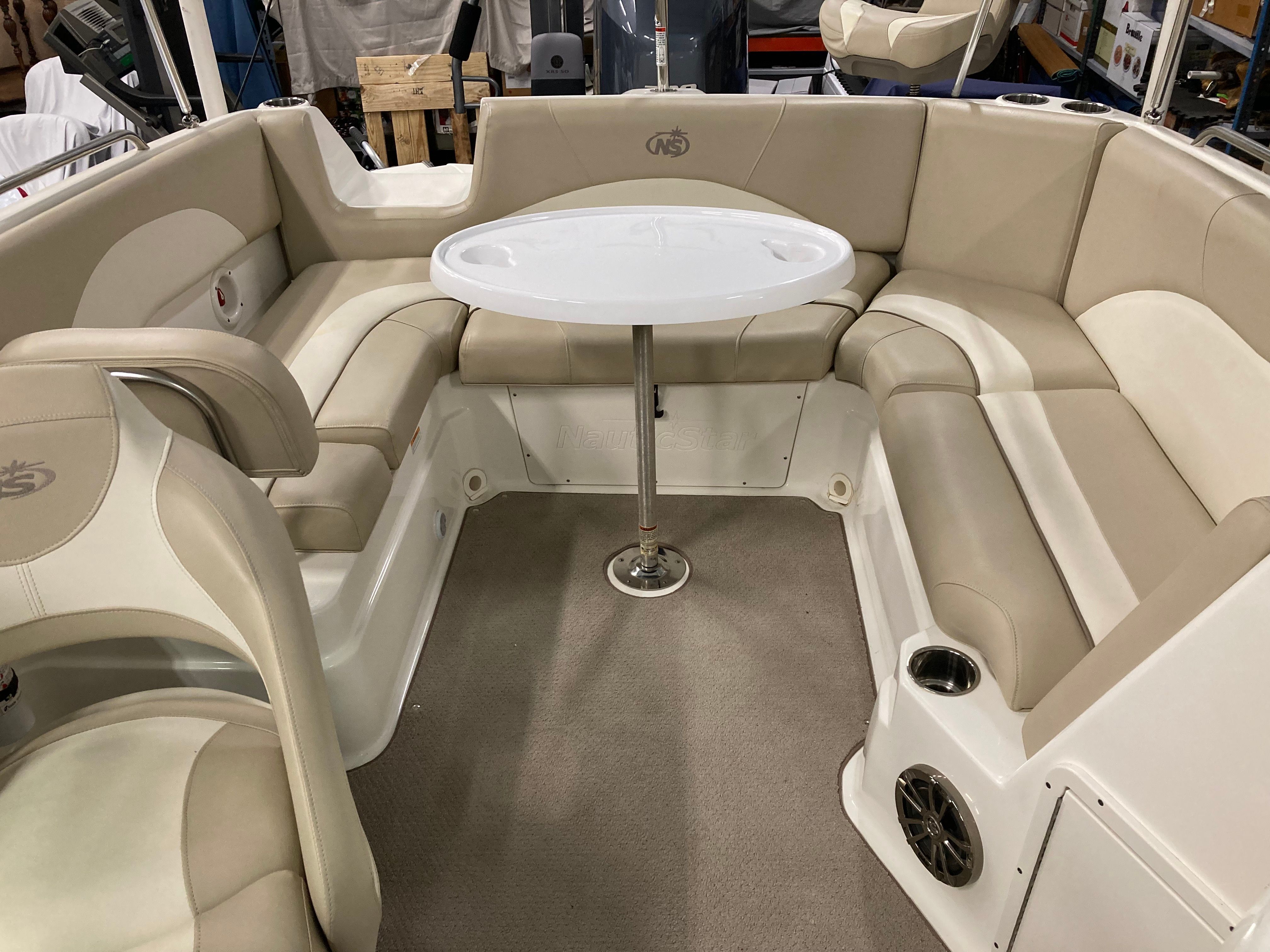 Interior of a Custom 223 DC boat with beige upholstered seating area and round table.