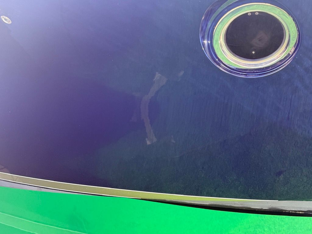 Close-up of a boat window with a green hull and blue background.