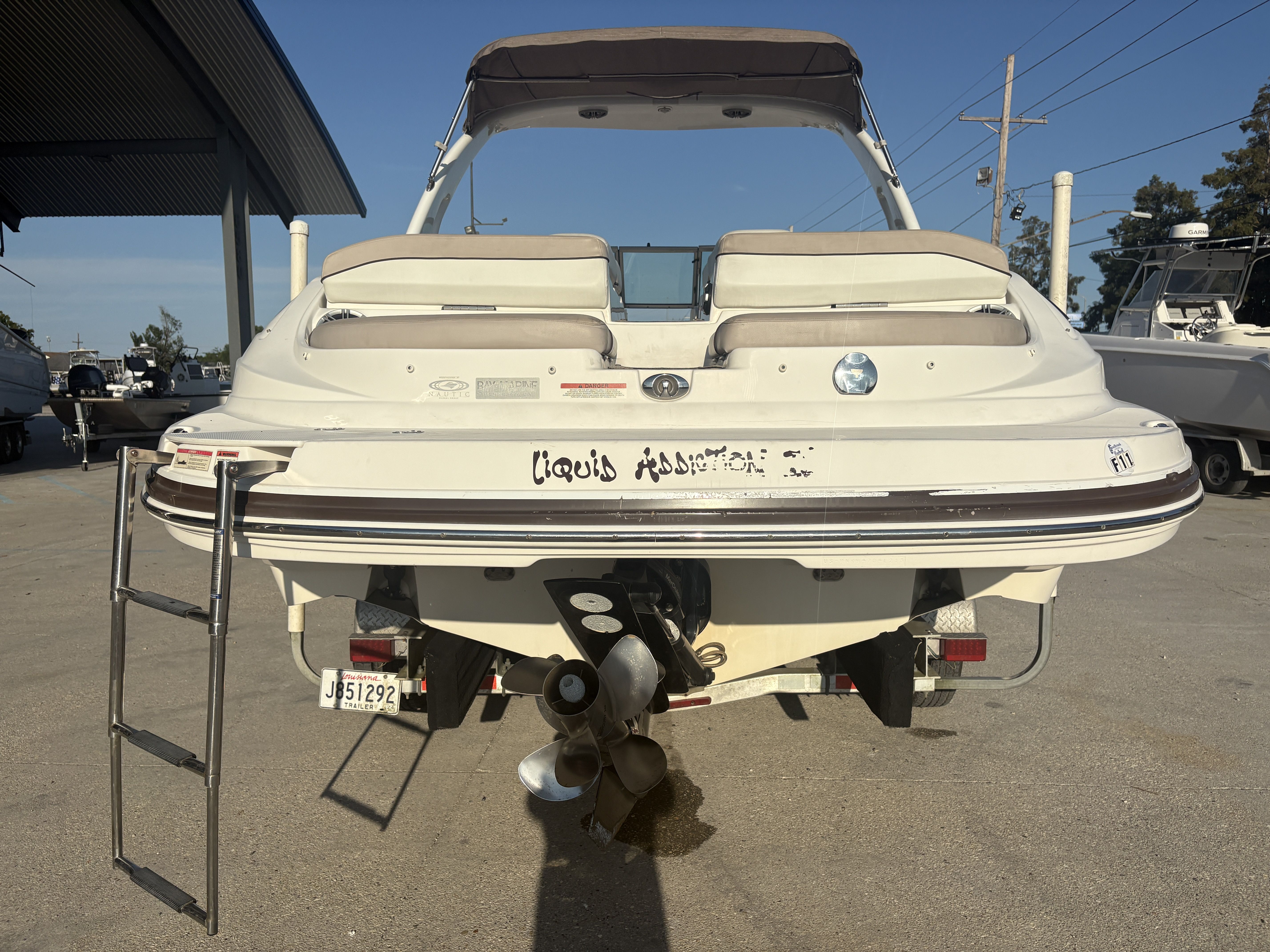 2013 Rinker Captiva 276 boat with ladder and propeller, parked on a trailer.