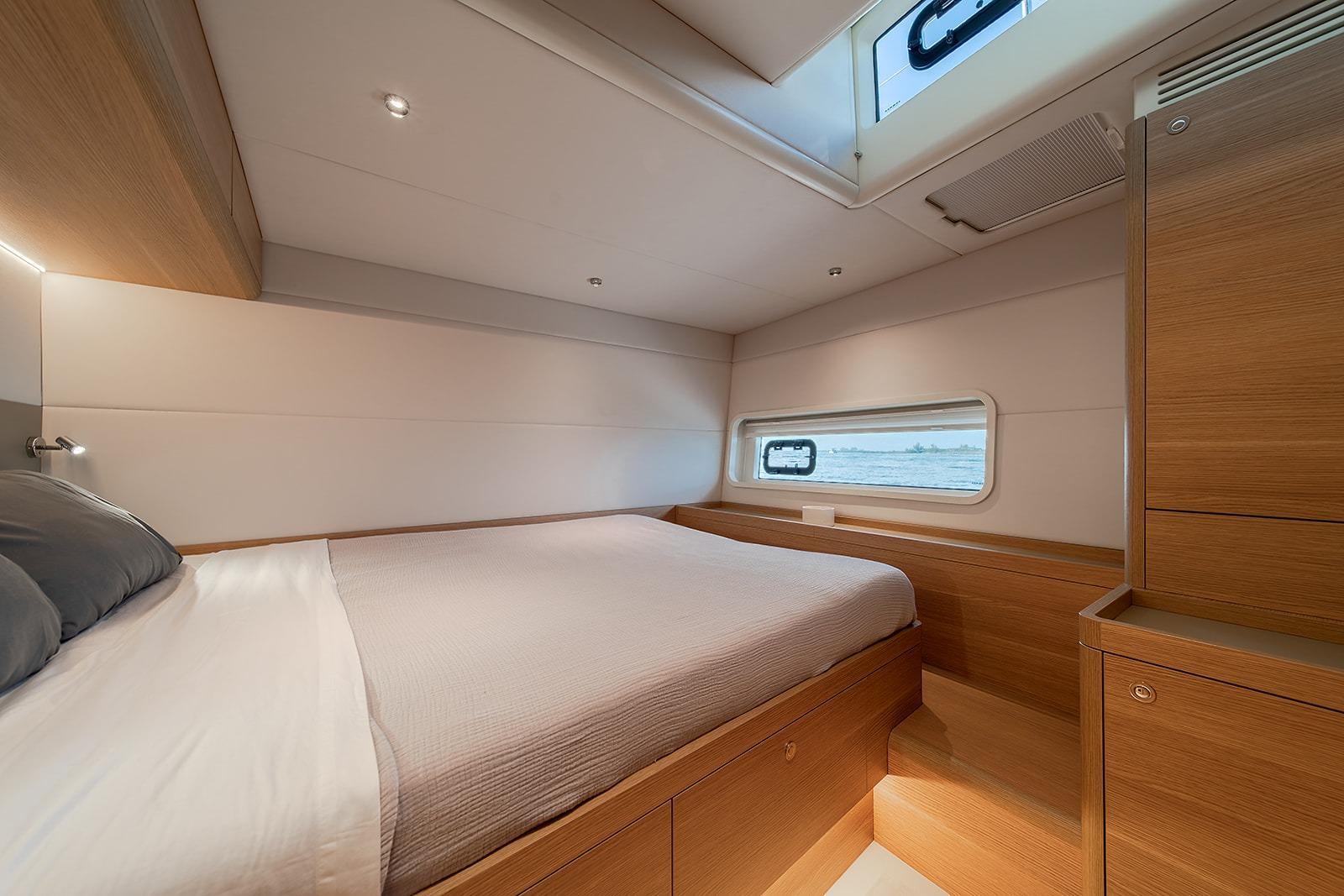 Luxurious cabin interior of 2026 Omikron Yachts OT-60, featuring modern wood finishes and cozy bedding.