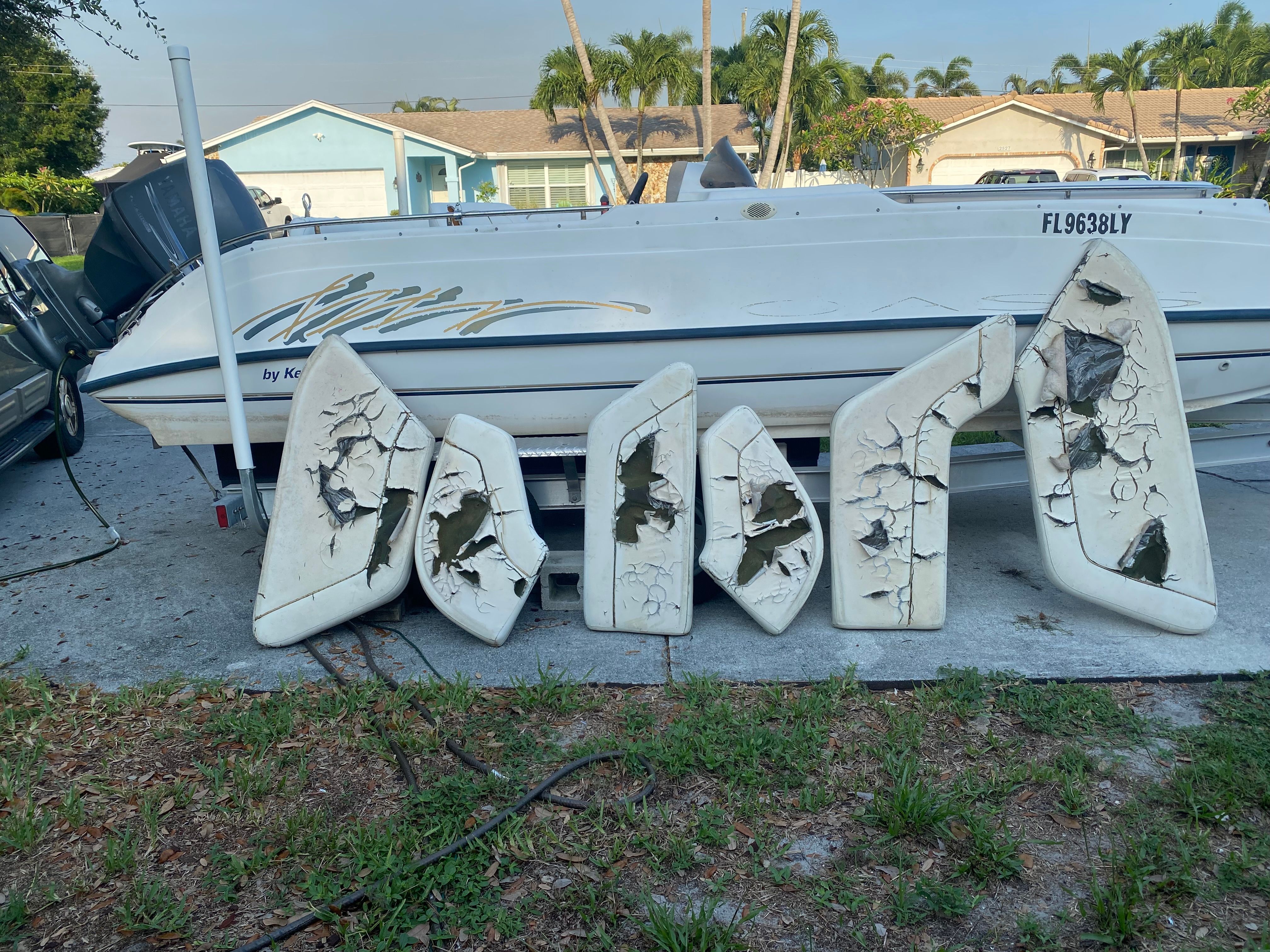 A 2002 Key West Oasis boat with damaged cushions on land.