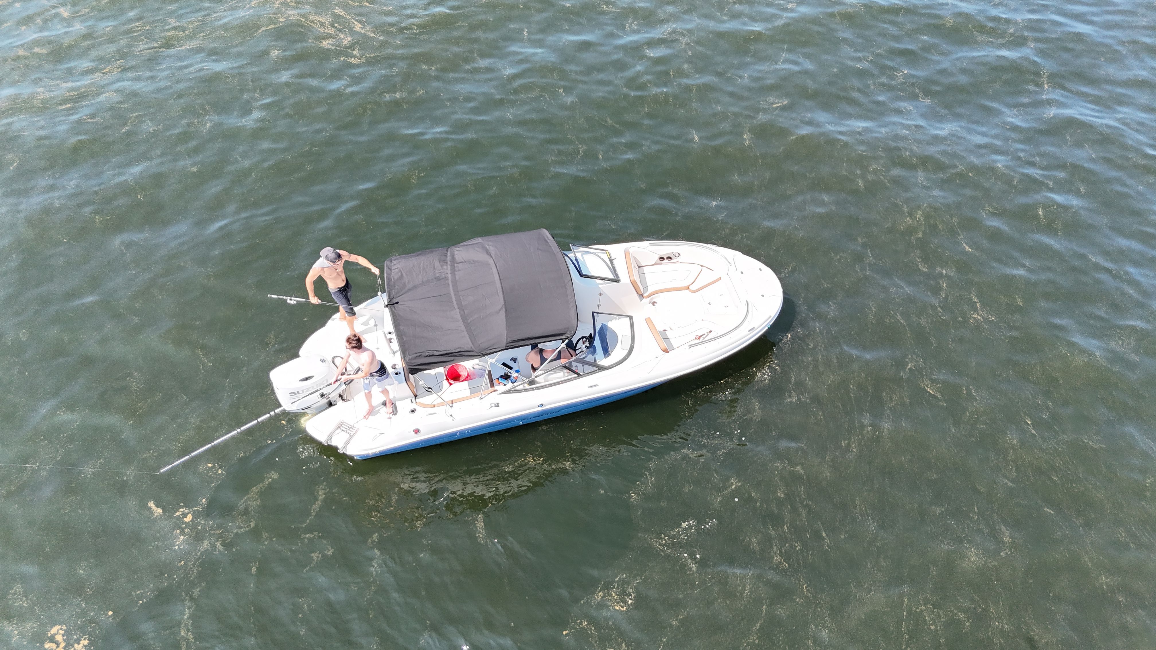 A boat with a black canopy is on the water, with people on board.