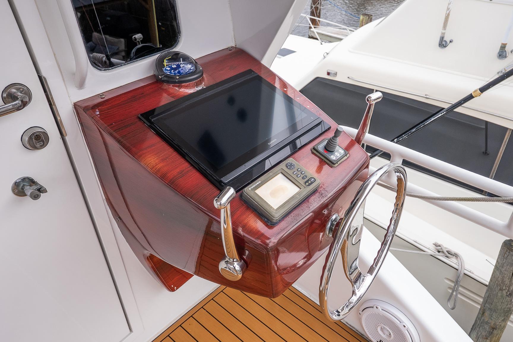 Control panel of 2002 Viking 61 Enclosed Bridge yacht with steering wheel and navigation equipment.