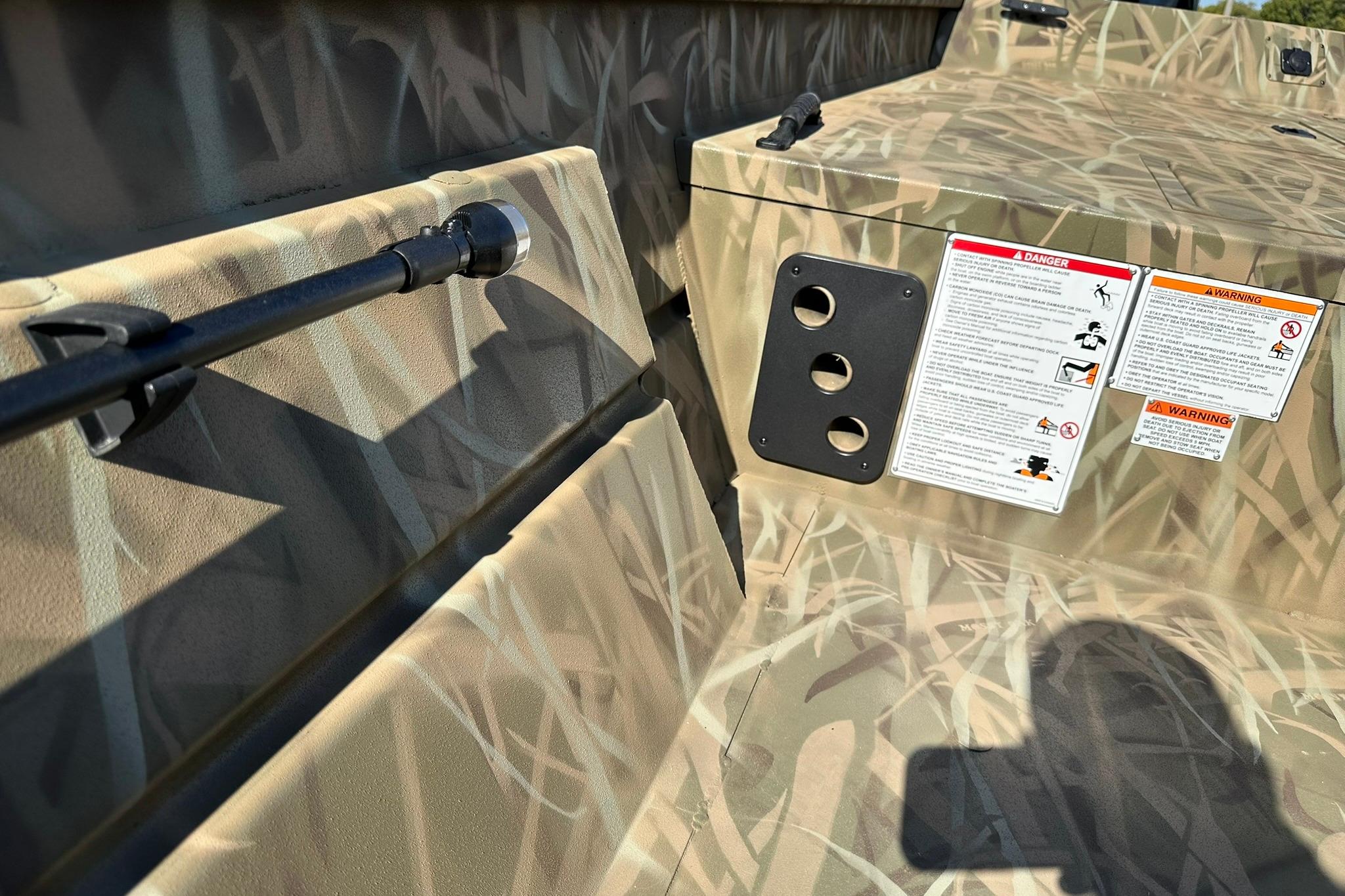Camouflage interior of 2026 Lowe Roughneck 2070CC boat with safety warnings and rod holder.