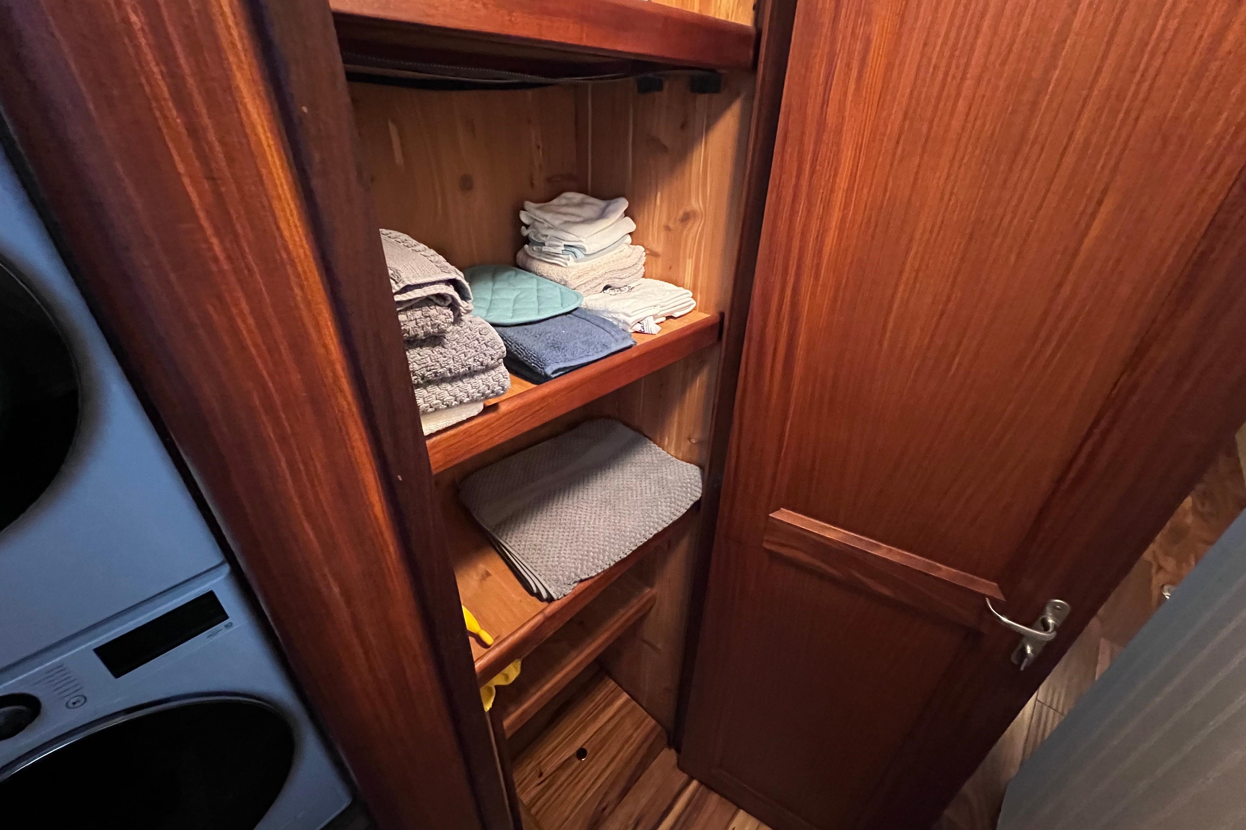 Wooden closet with neatly stacked towels on a 1987 Hatteras 70 Cockpit Motor Yacht.