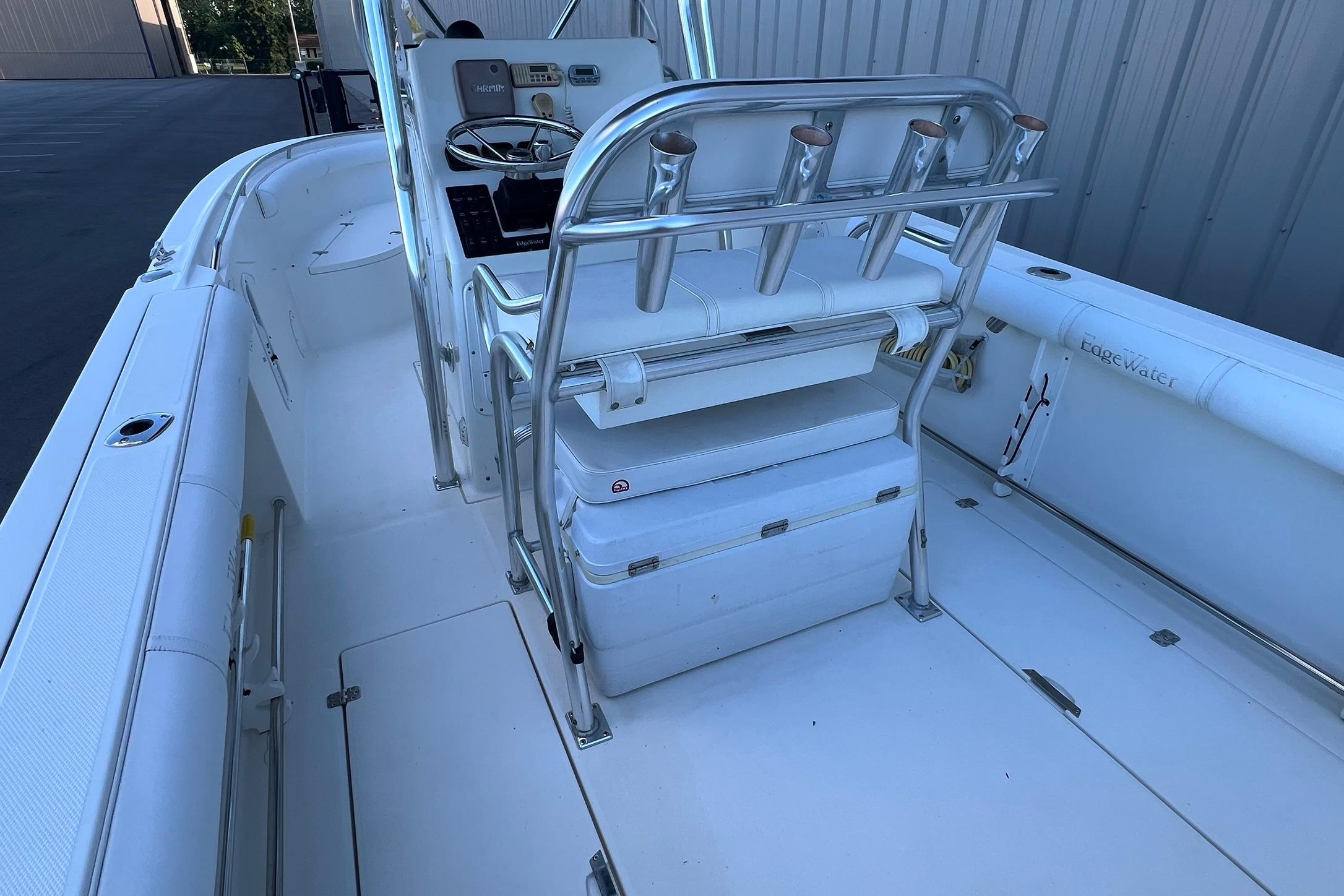 2006 Edgewater 245CC boat interior with seating and rod holders, docked near a building.