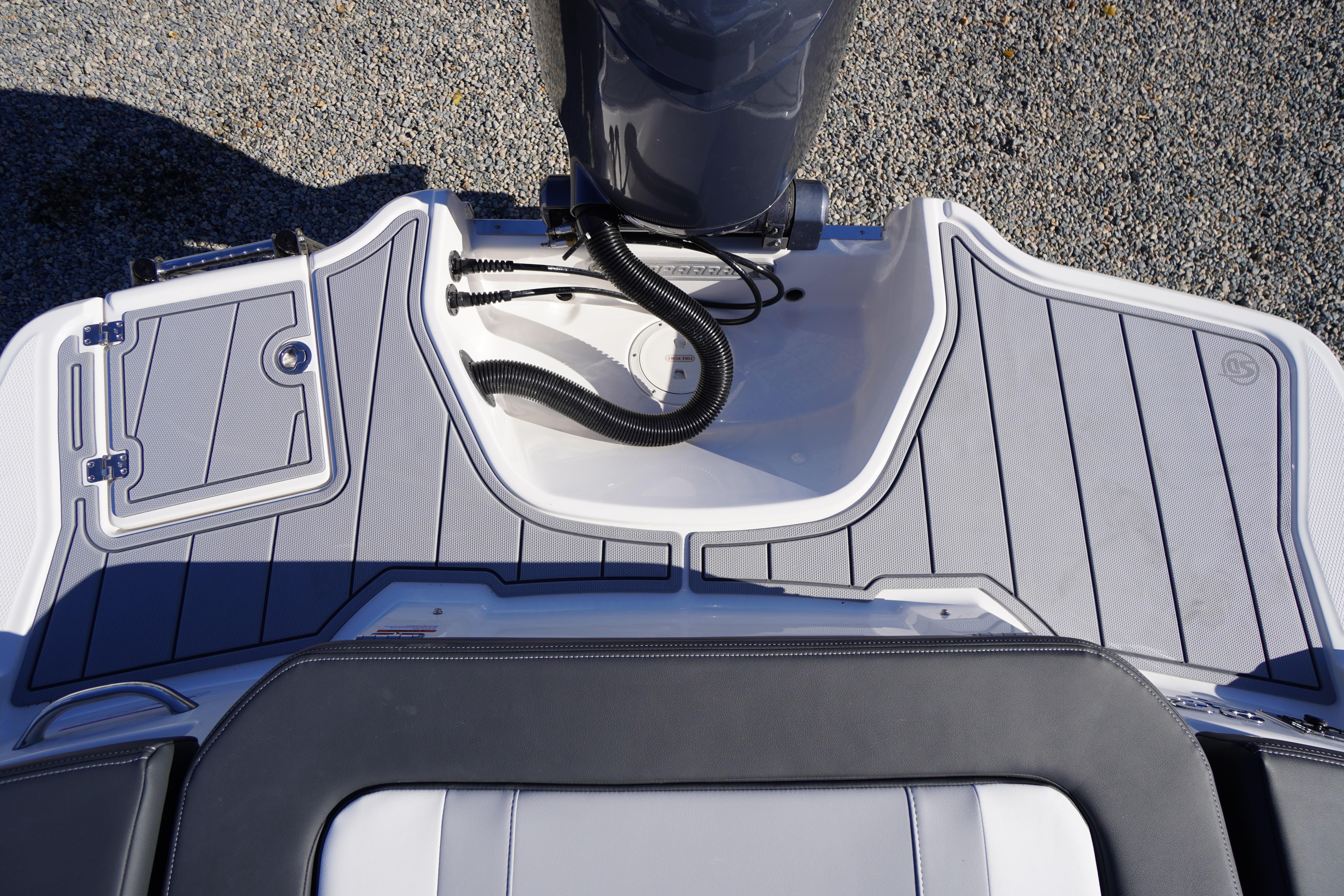 2026 Chaparral 23 SSi OB boat deck with outboard motor, featuring sleek design and storage compartment.