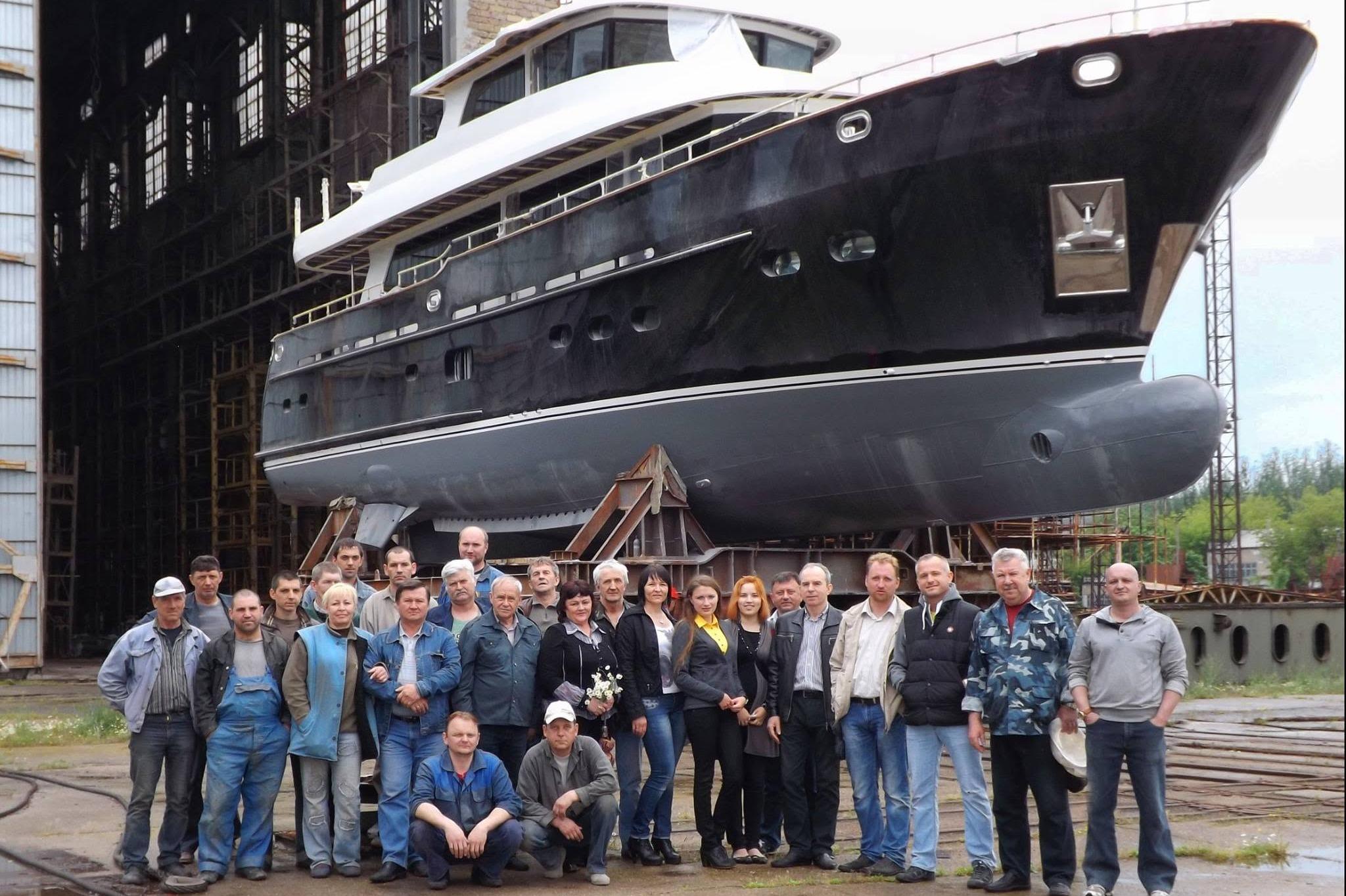 Group in front of 2014 Fifth Ocean Yachts 24m Displacement Explorer Yacht in shipyard.