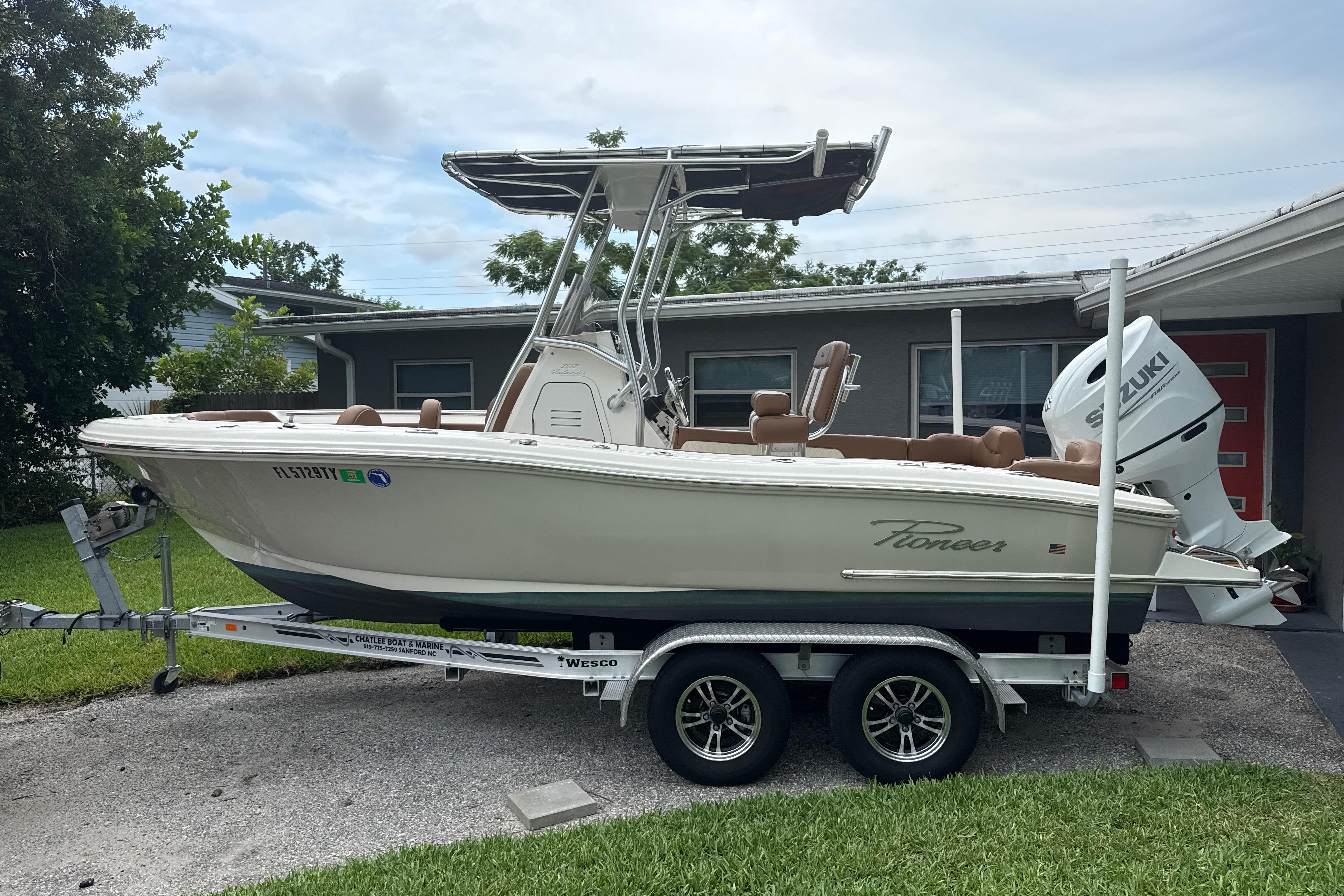 2023 Pioneer 202 Islander boat on trailer, parked in driveway, featuring Suzuki outboard motor.
