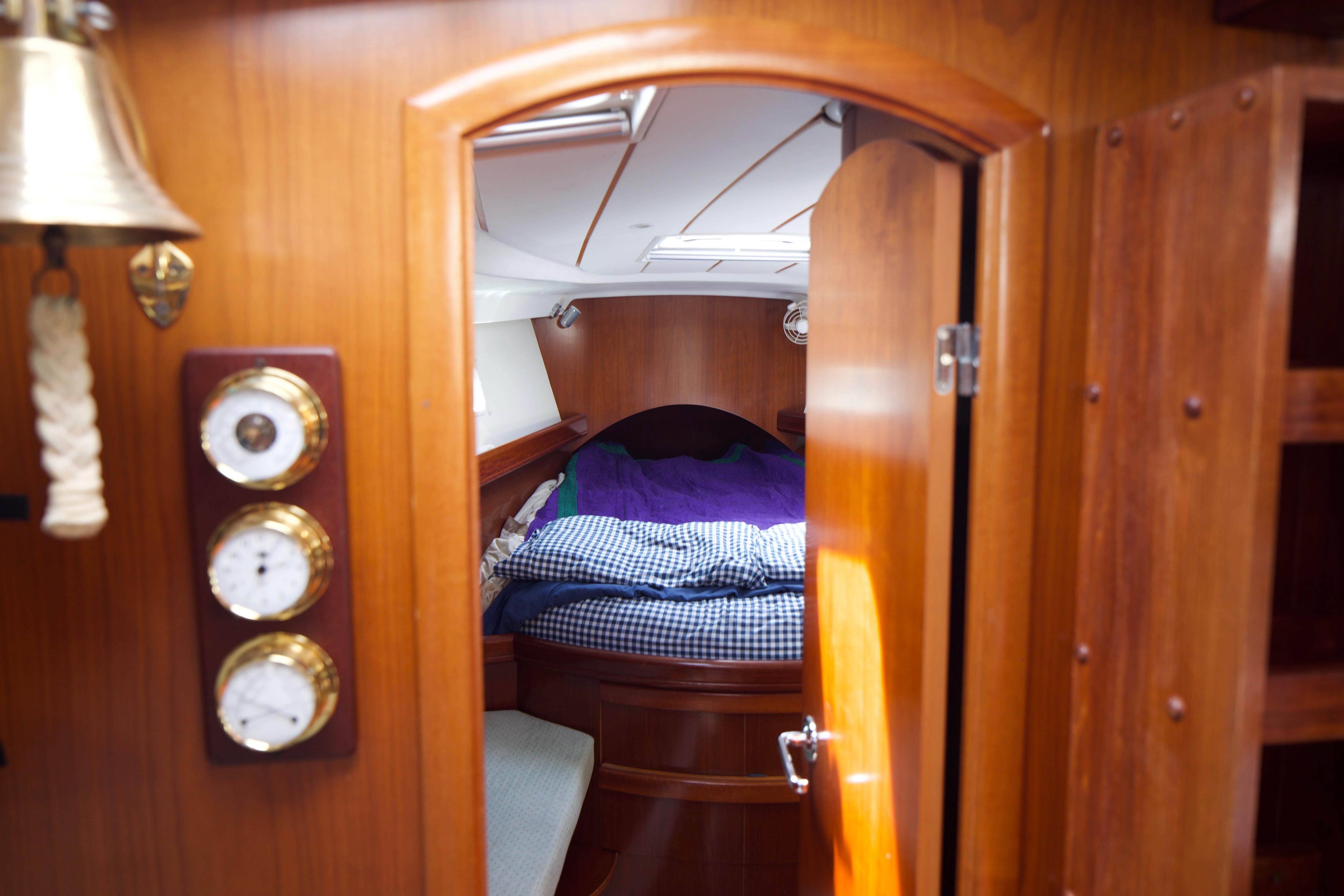 Interior cabin of 2005 Beneteau 423 yacht, featuring cozy bedding and wooden furnishings.