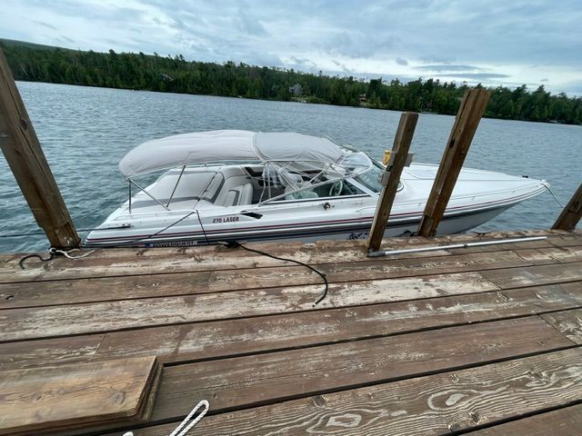 A white 1992 Powerquest 270 Laser boat docked at a wooden pier on calm water.