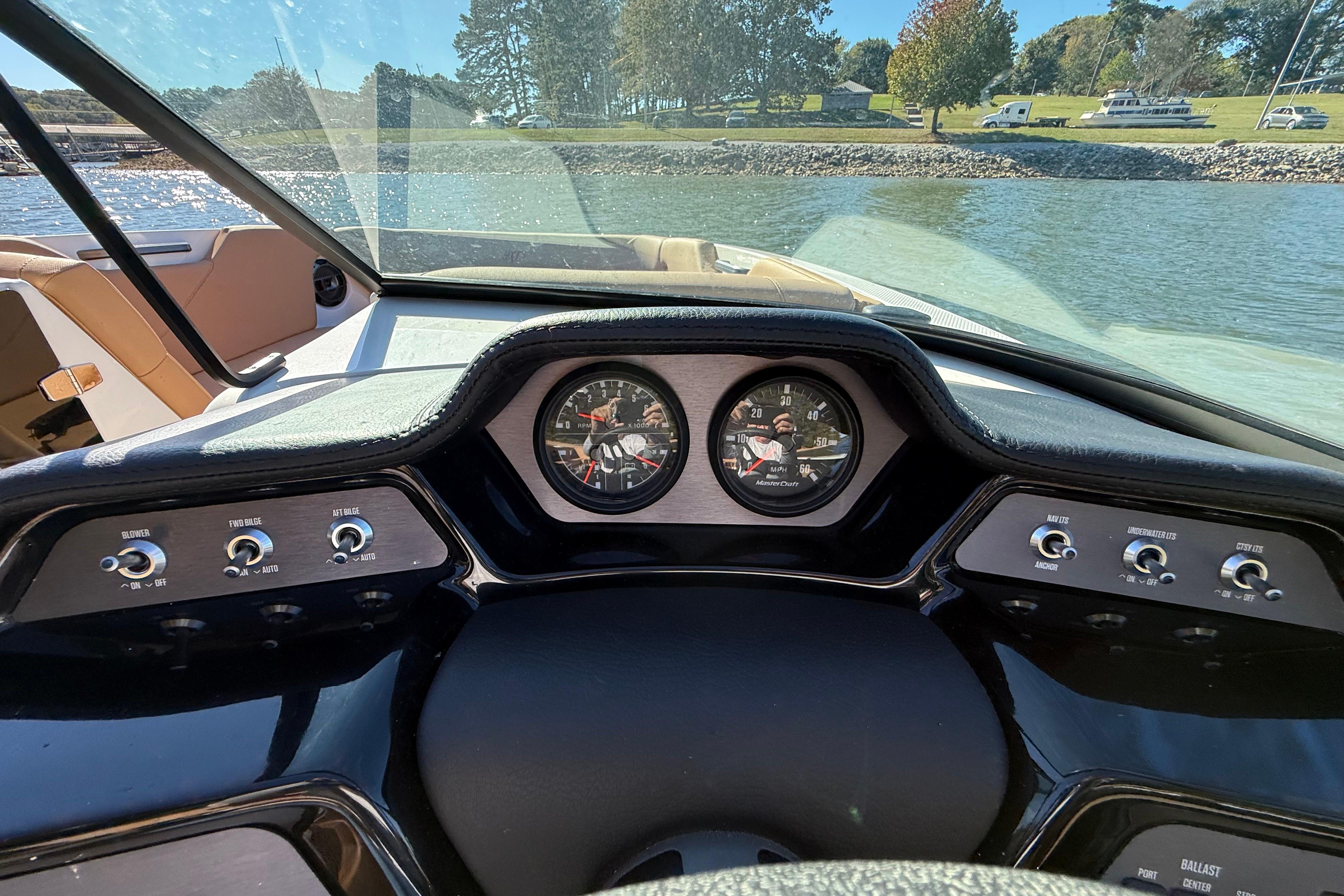 2022 MasterCraft NXT24 dashboard with gauges and controls, overlooking a scenic lake view.