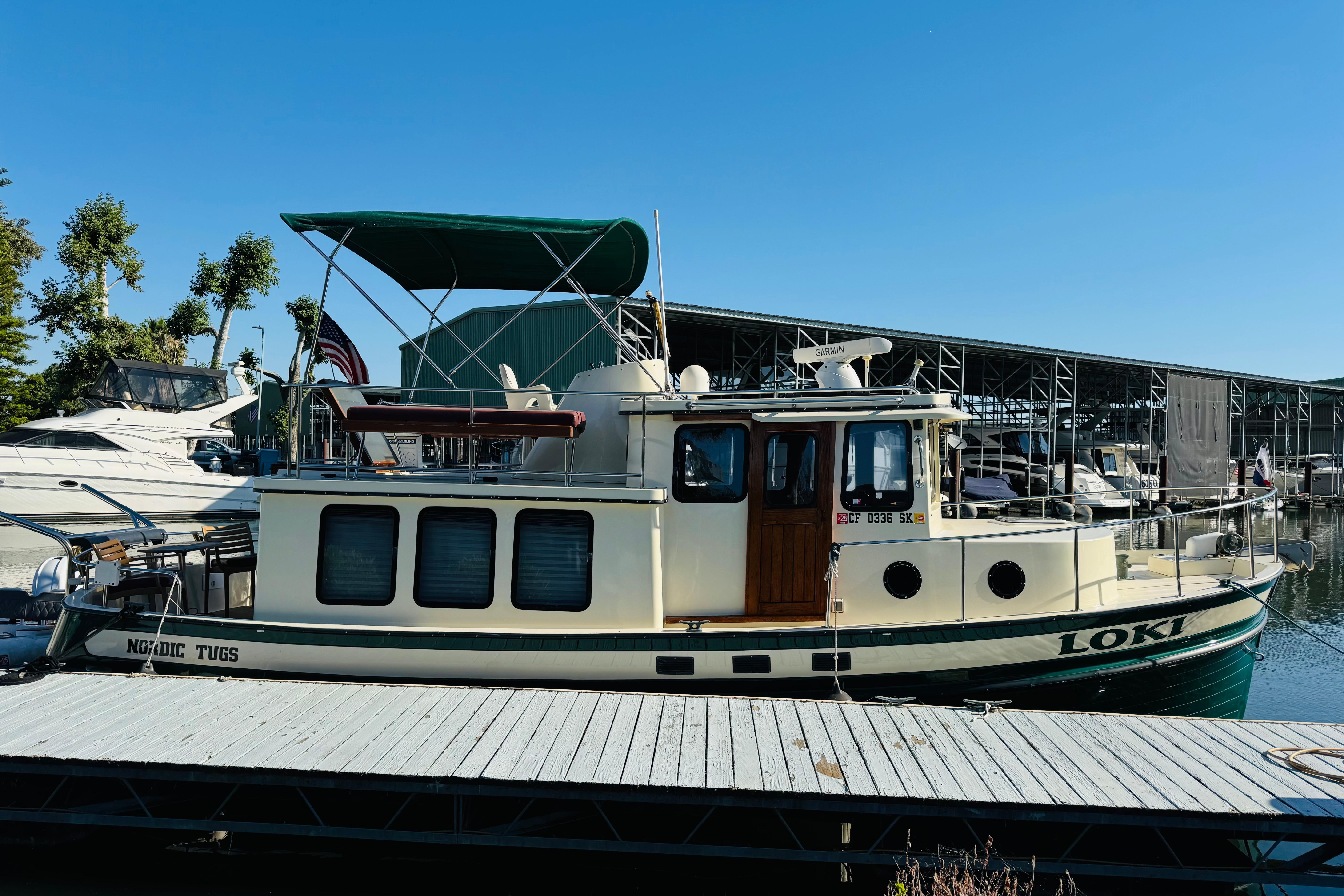 1996 Nordic Tug 32 docked at marina, featuring green canopy and classic design.