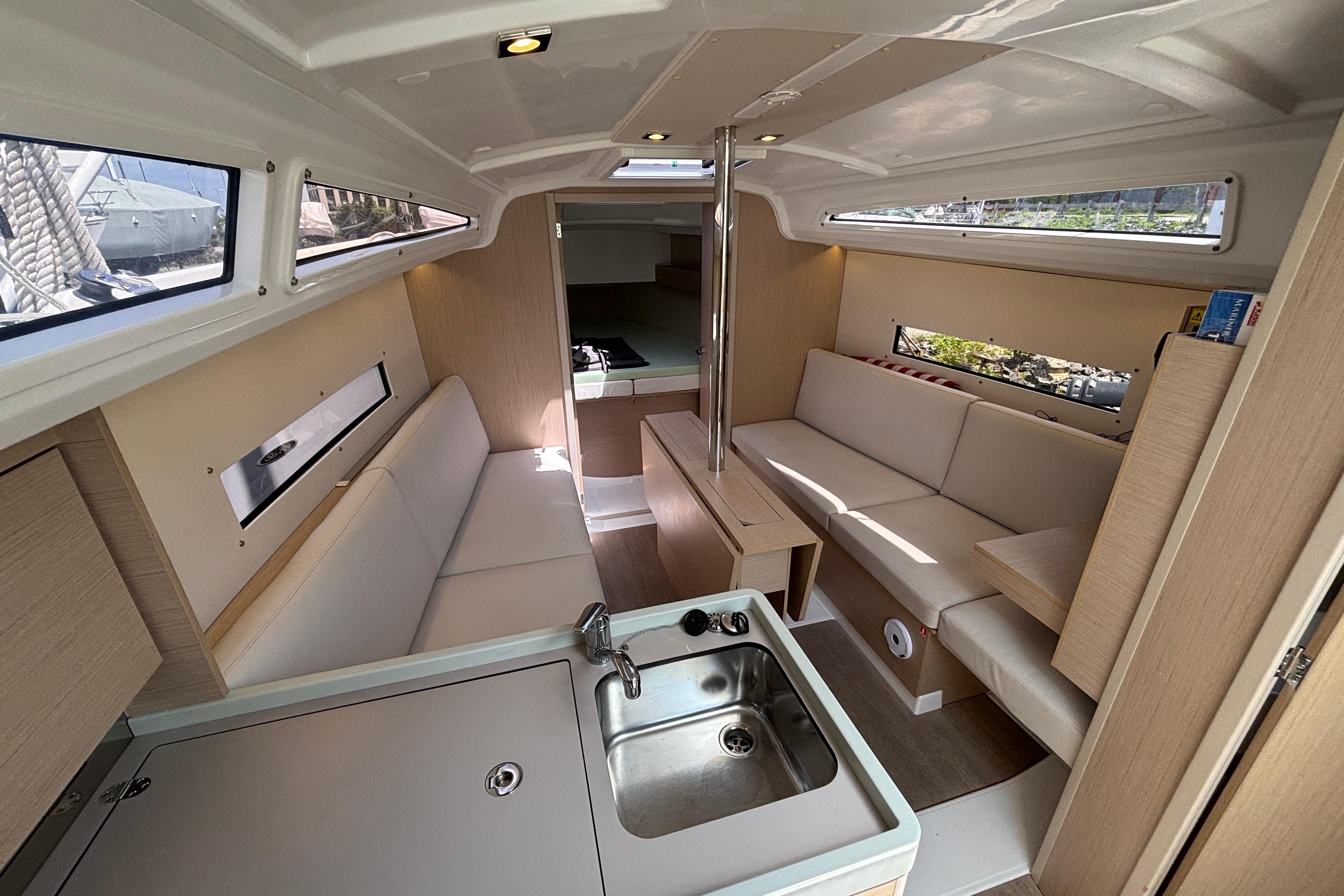 Interior of 2021 Beneteau Oceanis 30.1 yacht, featuring modern seating and compact kitchen area.