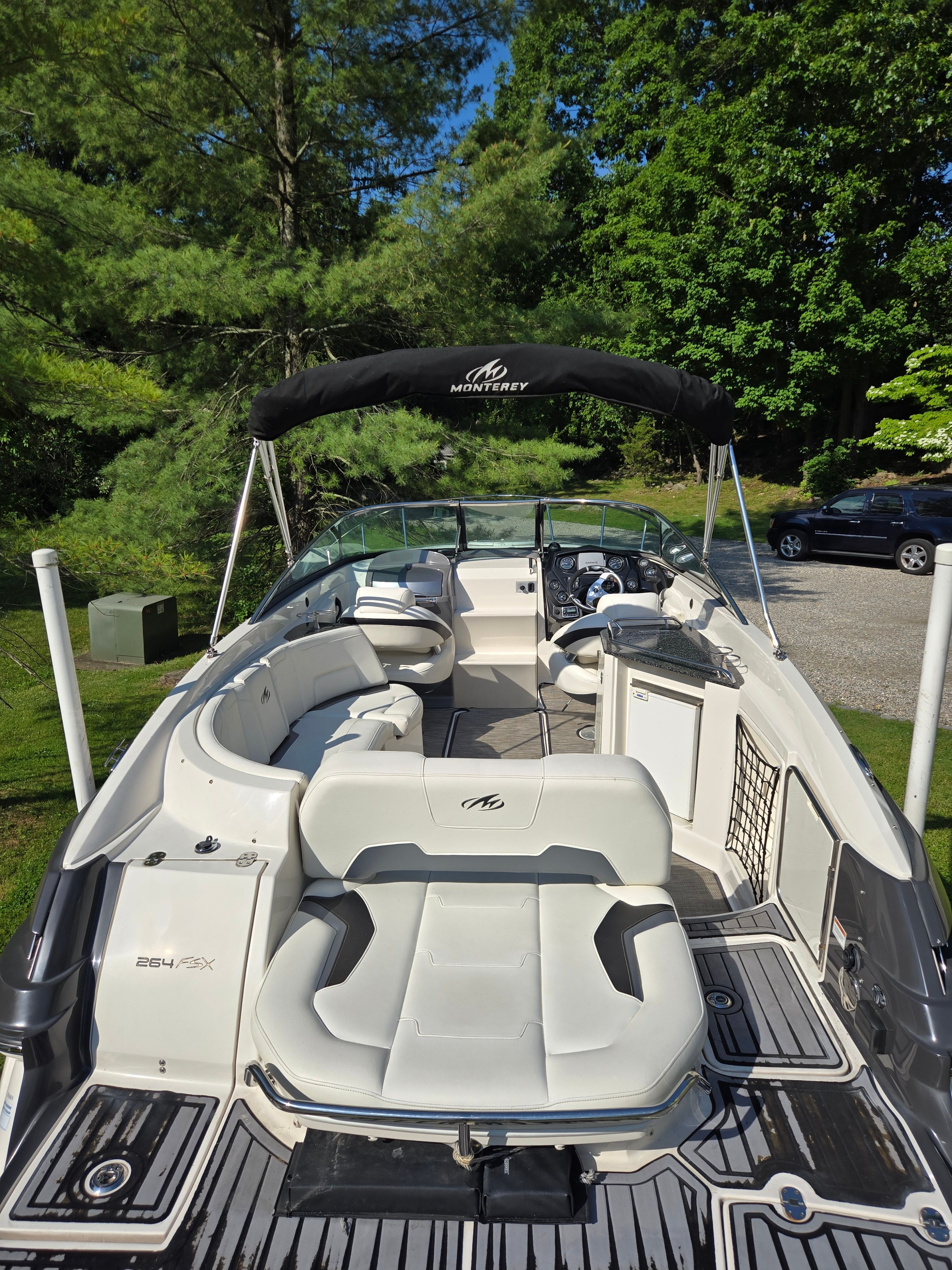 A Monterey 264 boat is on a trailer in a green, wooded area.