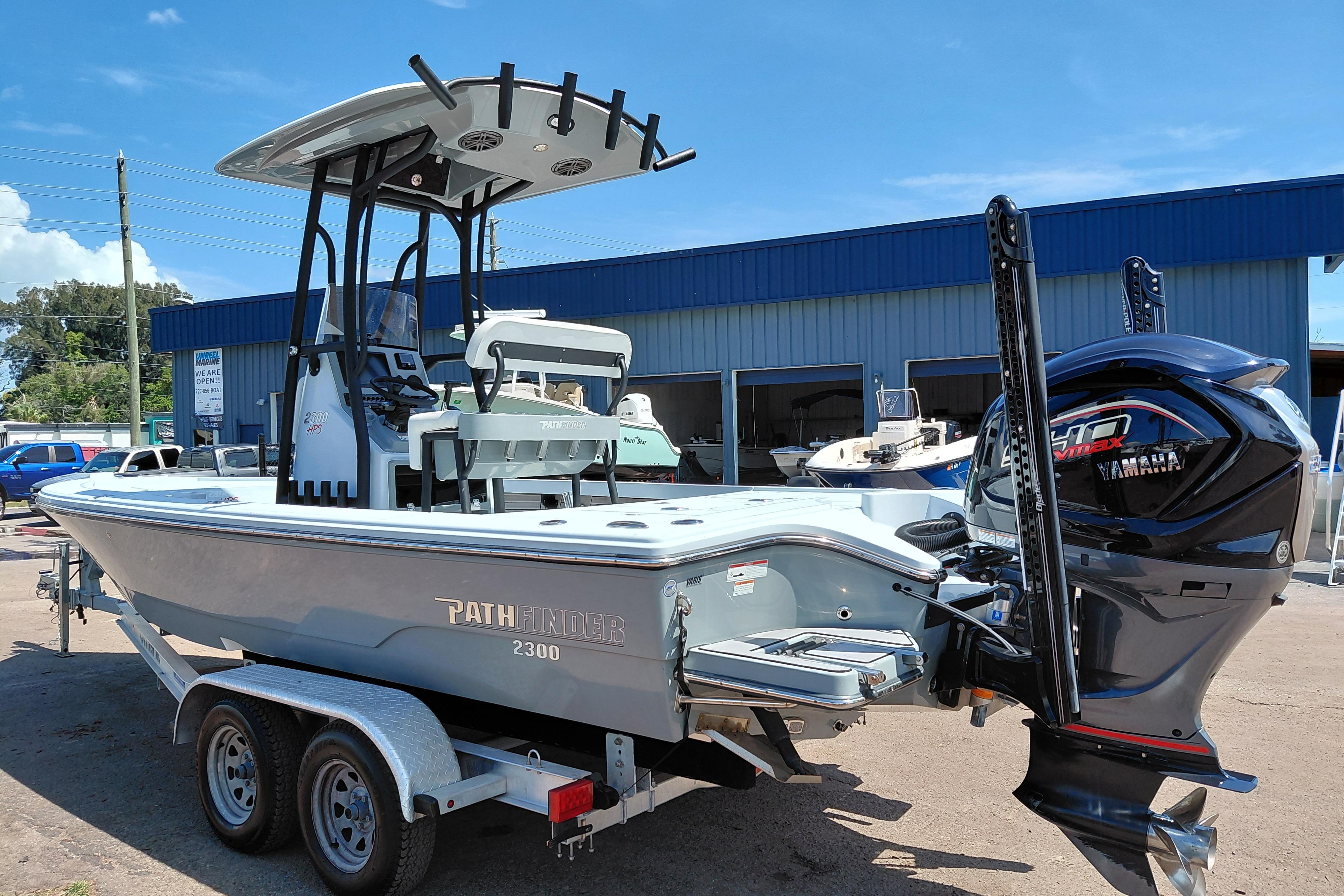 2022 Pathfinder 2300 HPS boat with Yamaha engine on trailer, parked outside a building.